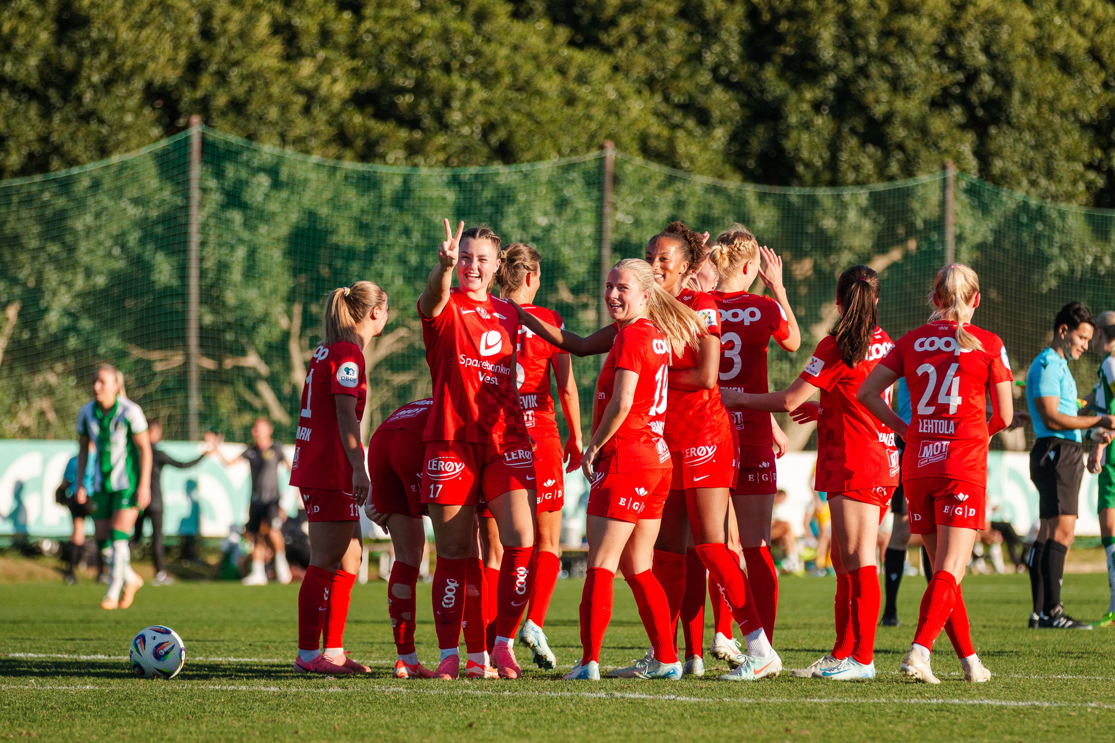 Foto av Brann Kvinner som feirer sammen i sola på fotballbanen.