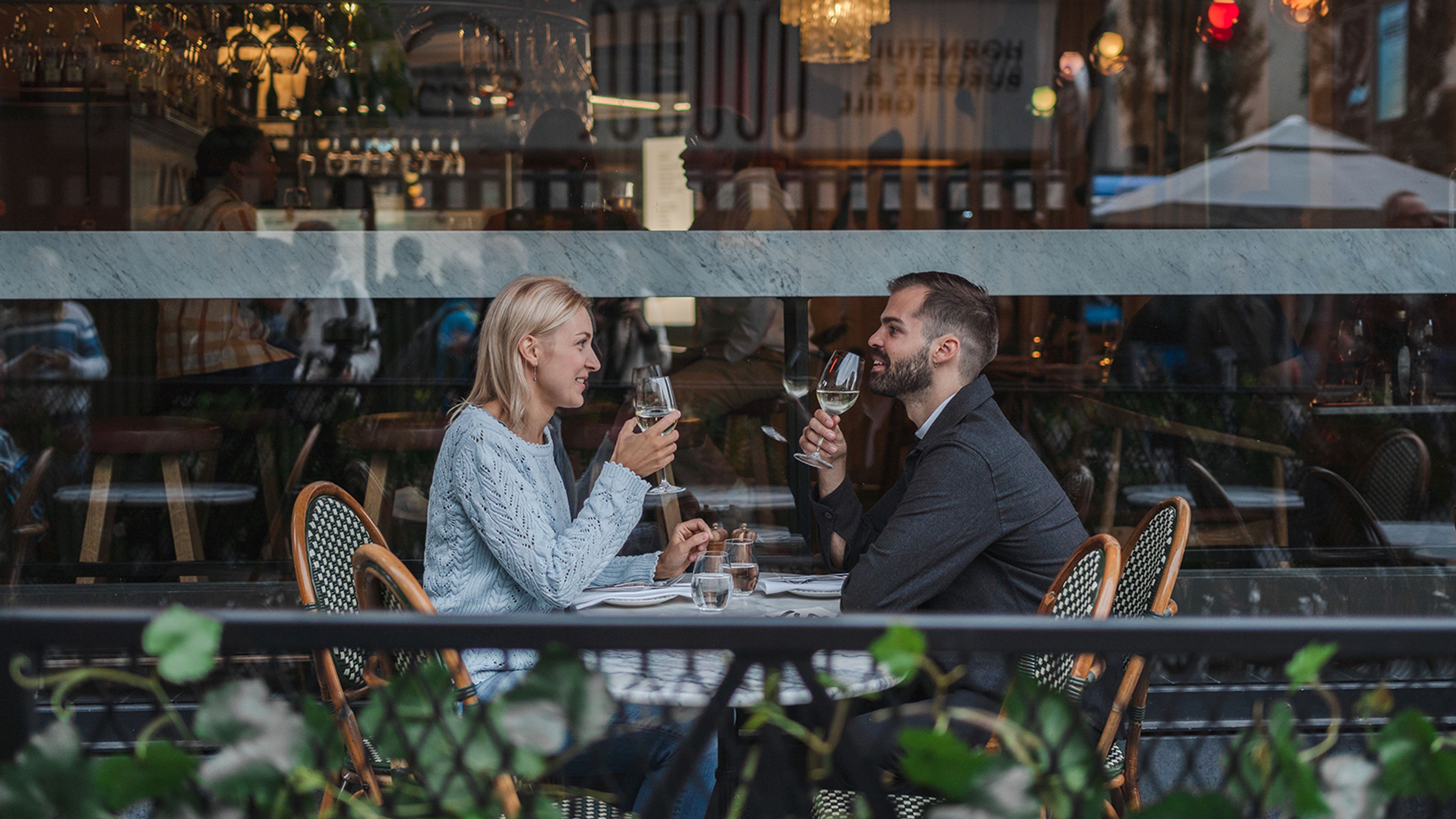 kvinna och man sitter och dricker ur vinglas