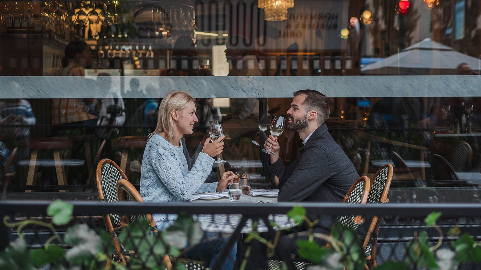 kvinna och man sitter och dricker ur vinglas