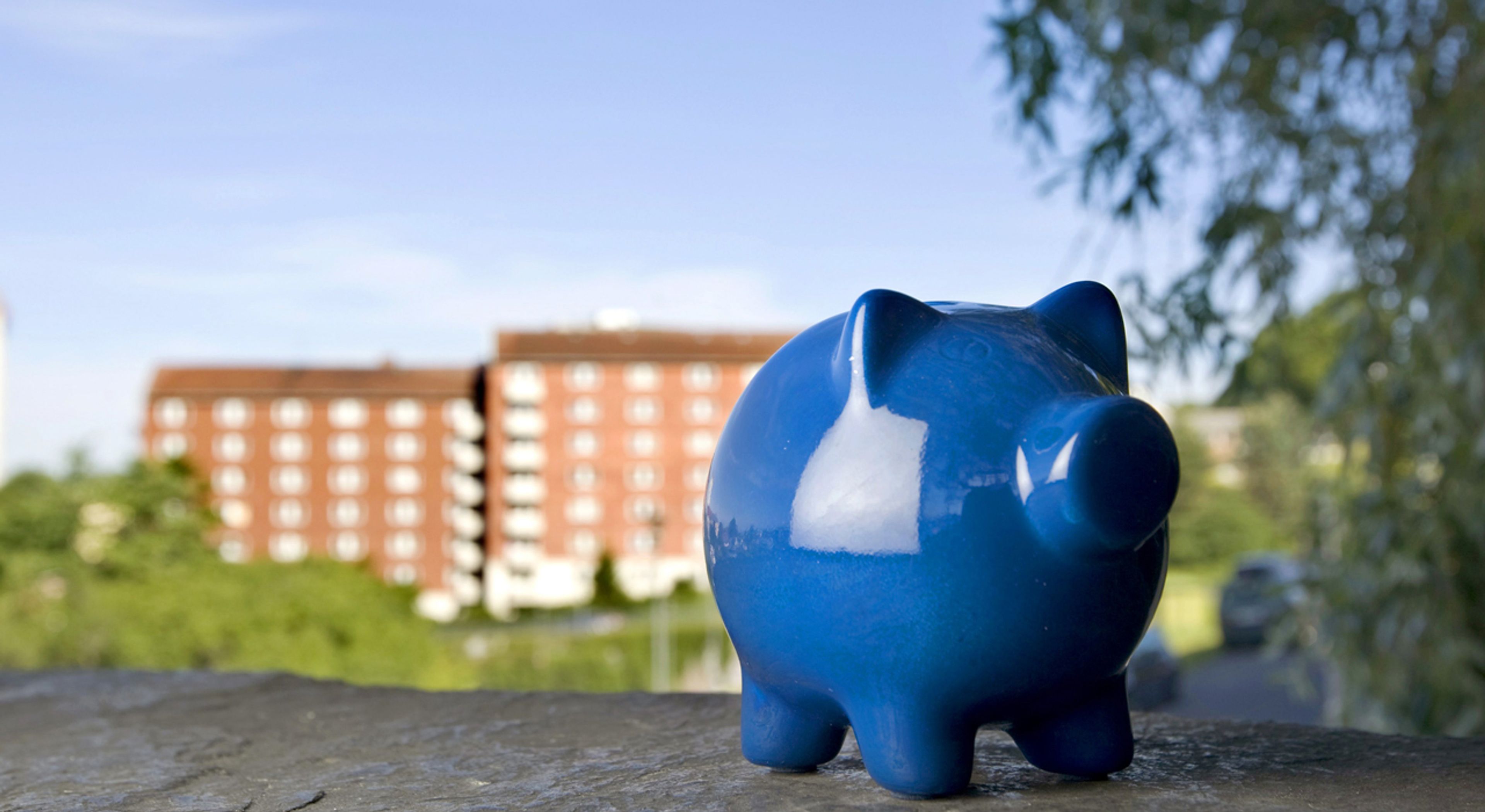En blå sparegris foran en boligblokk