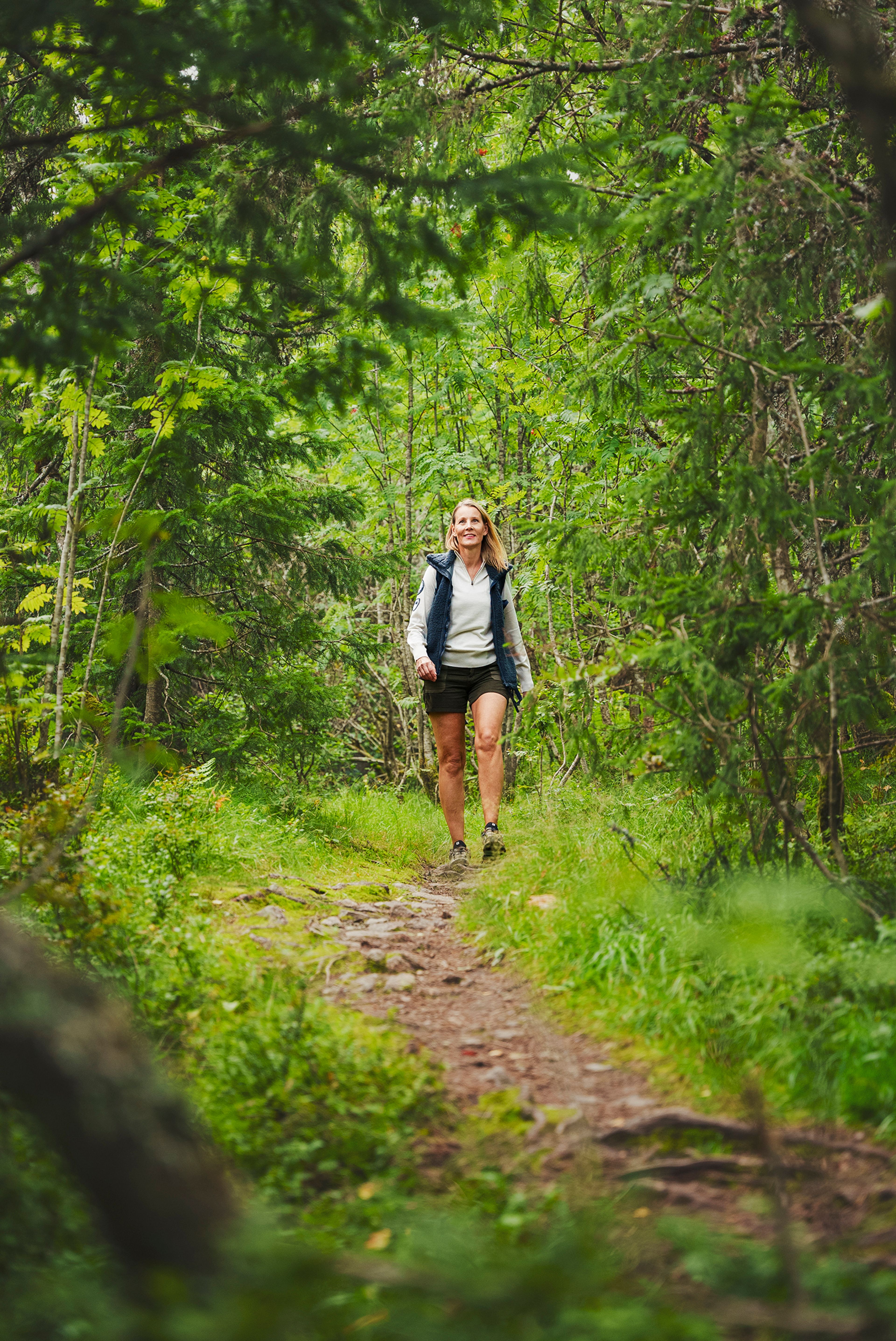 Kvinne som går tur på skogssti i skogen