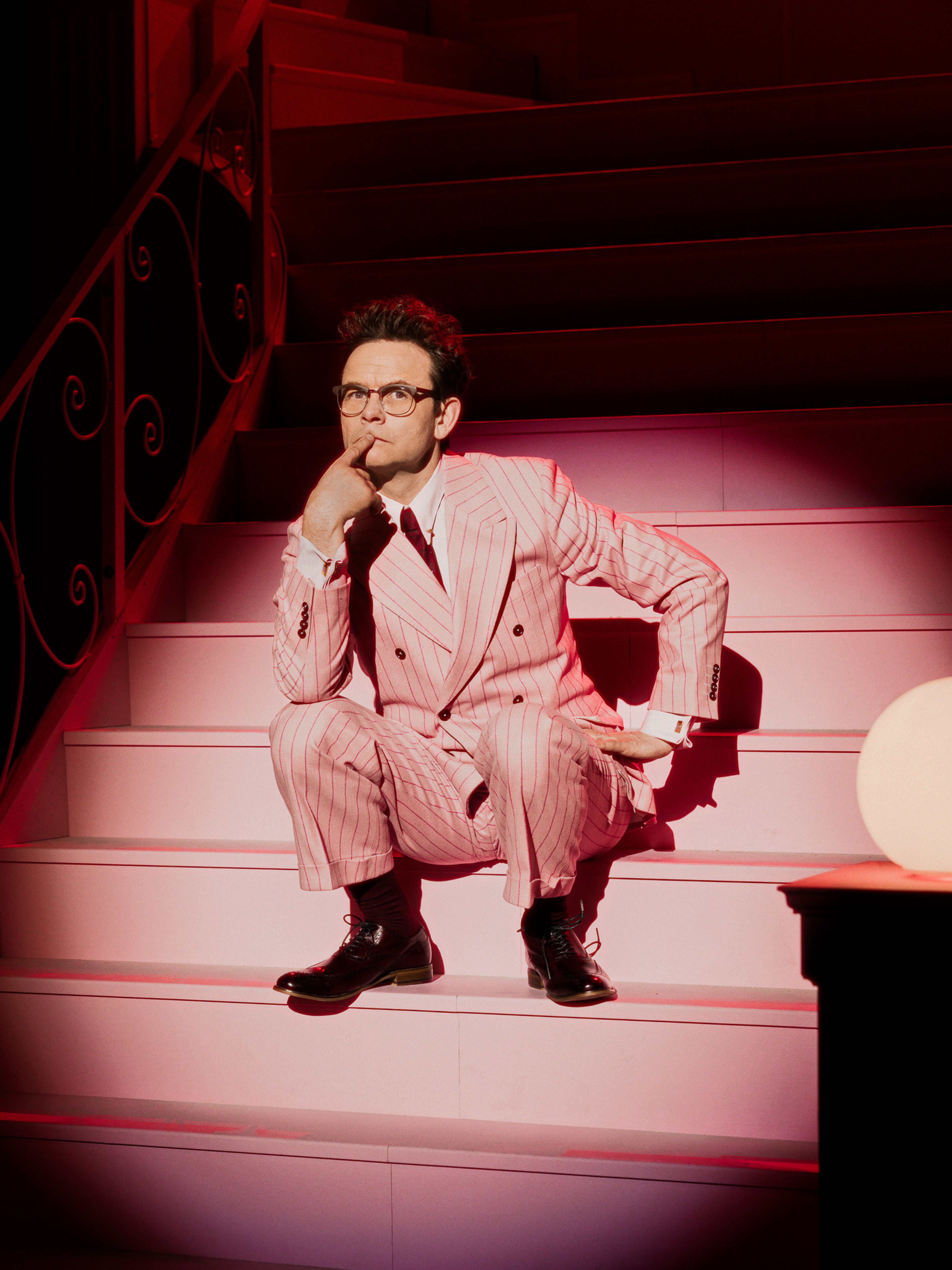 Foto av Jan Gunnar Røise i en rosa dress. Han sitter i en trapp på nationaltheateret.