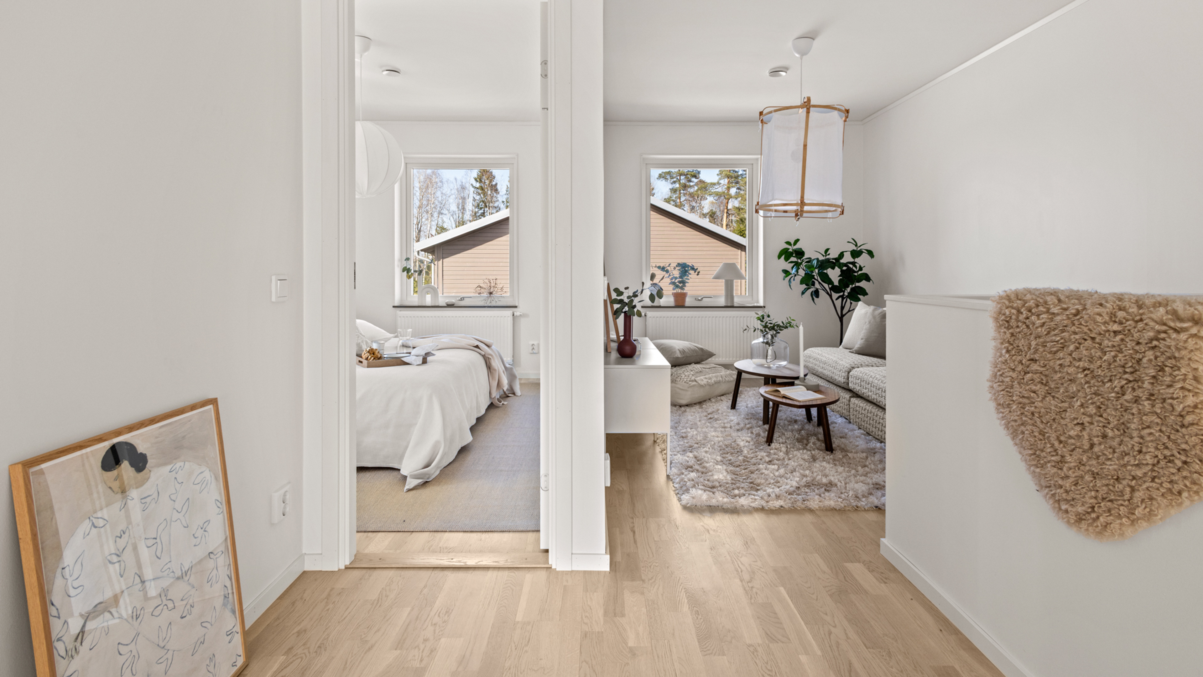 Bild på ovanvåningen i ett radhus där man ser in i stora sovrummet och mot allrummet med soffa och TV