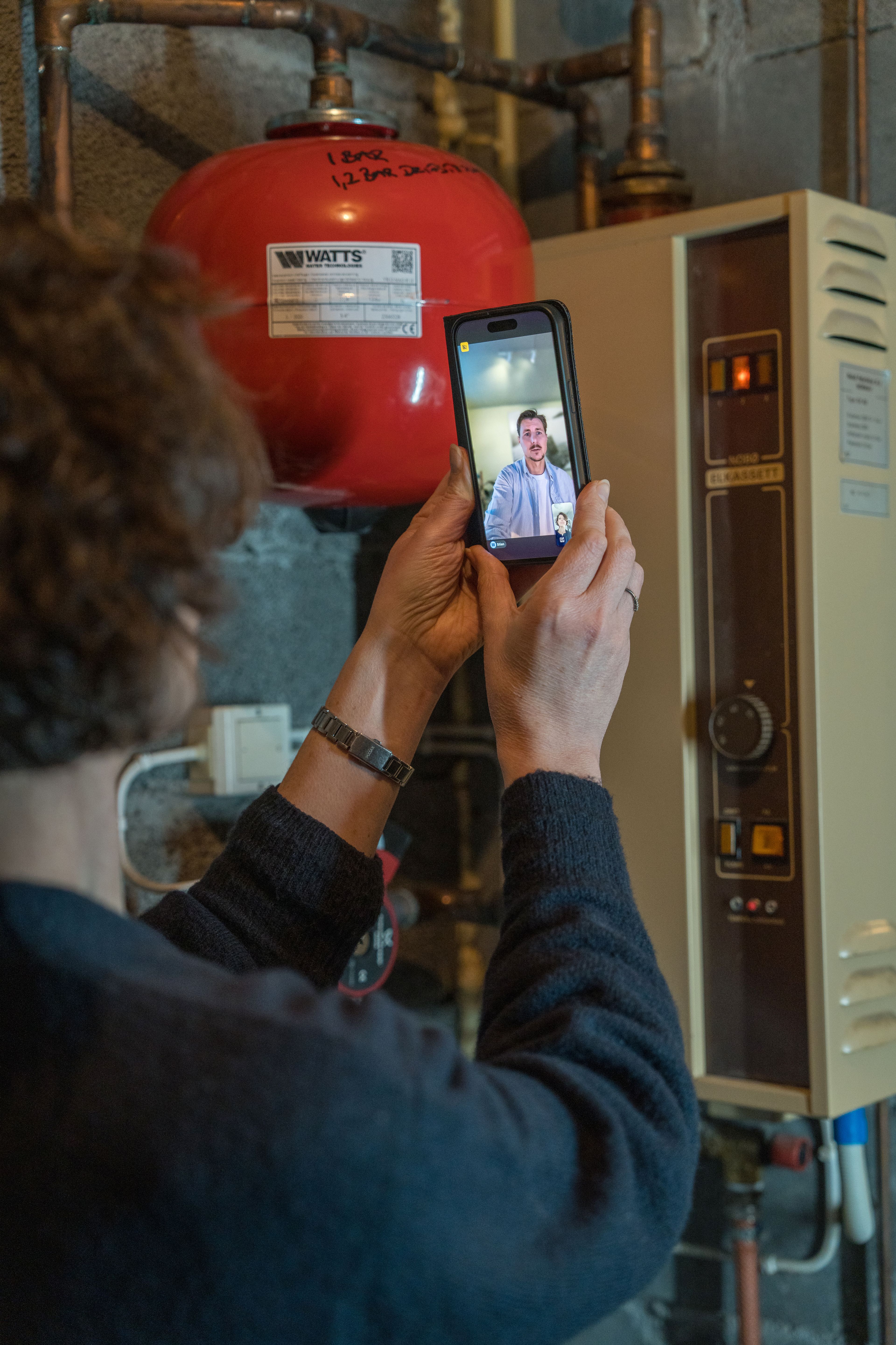 Marion Vik viser fram det gamle varmeanlegget i kjelleren, mens hun er i videosamtalen med Eeffy
