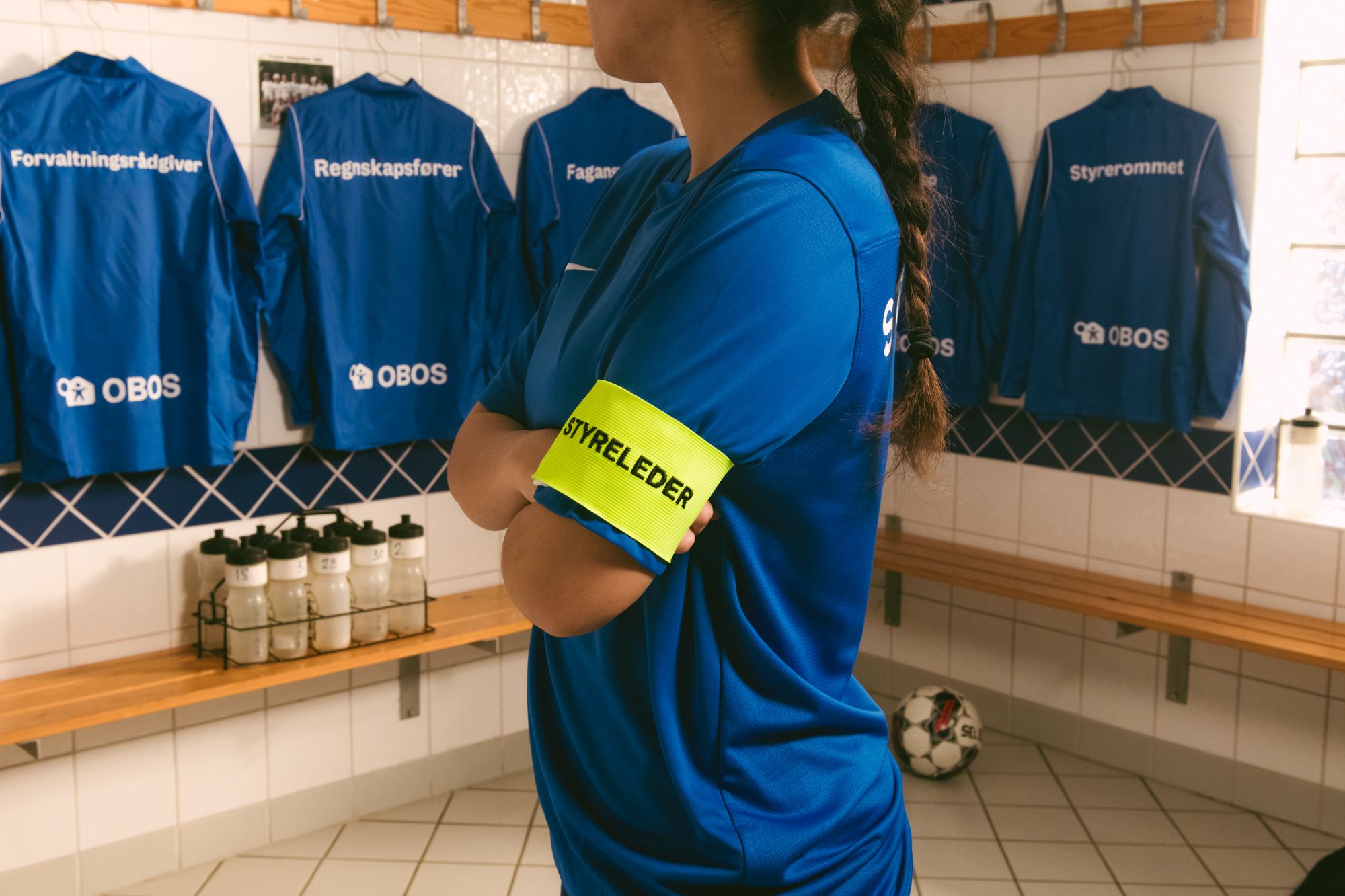 Kvinne i garderobe med armbånd med teksten styreleder. 
