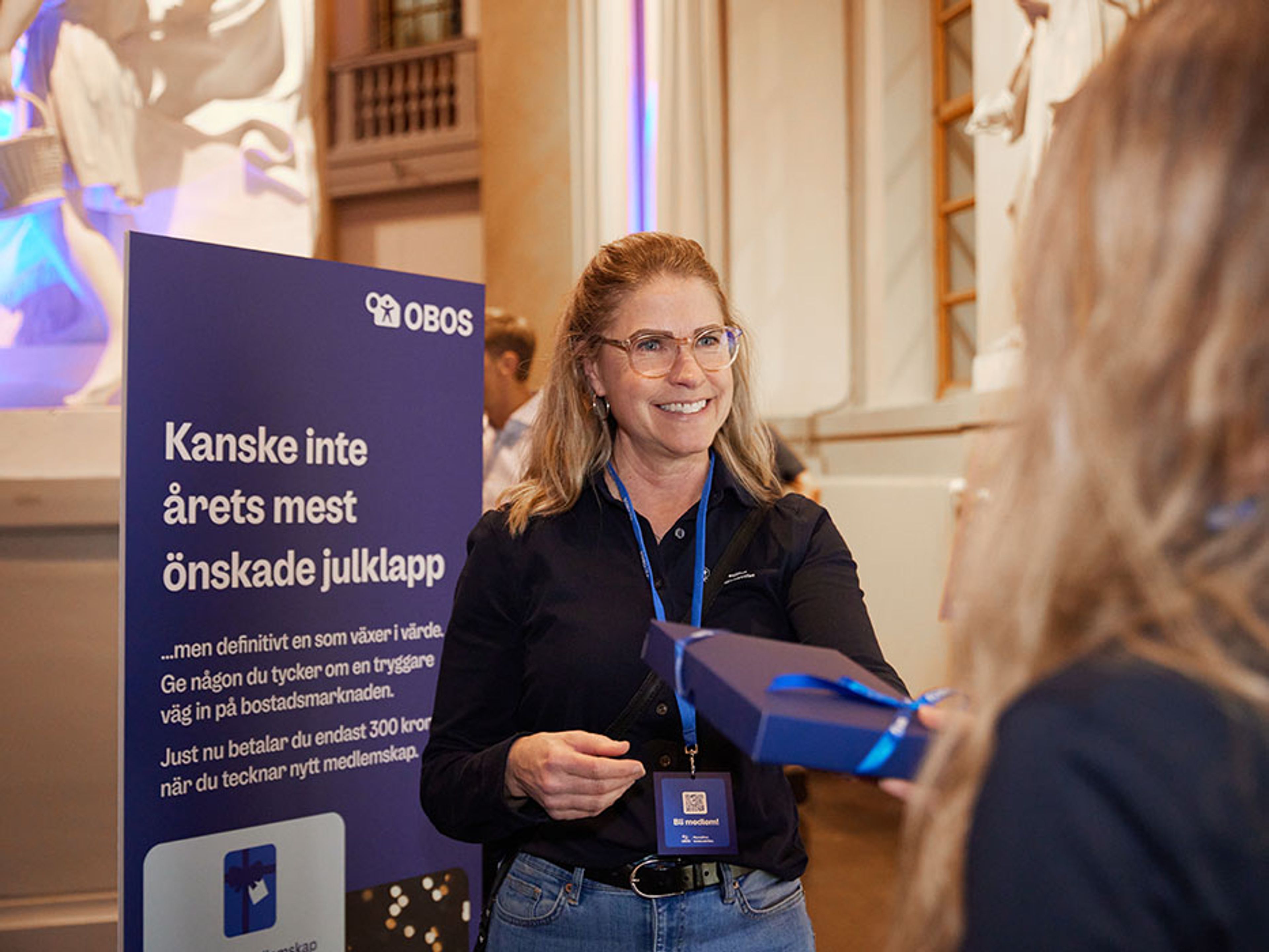 OBOS-personal ger ut inslagen julklapp till medlem som tecknat medlemskap