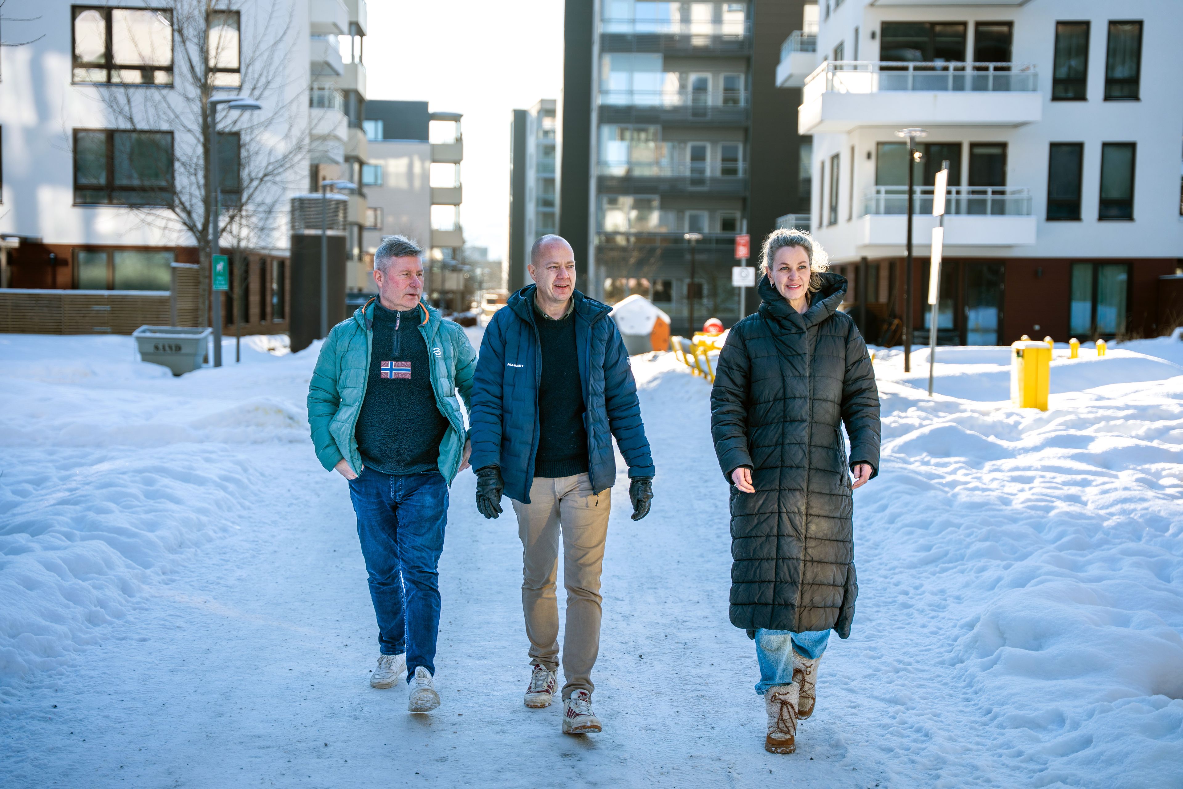 Tre personer går bortover en snølagt gangvei