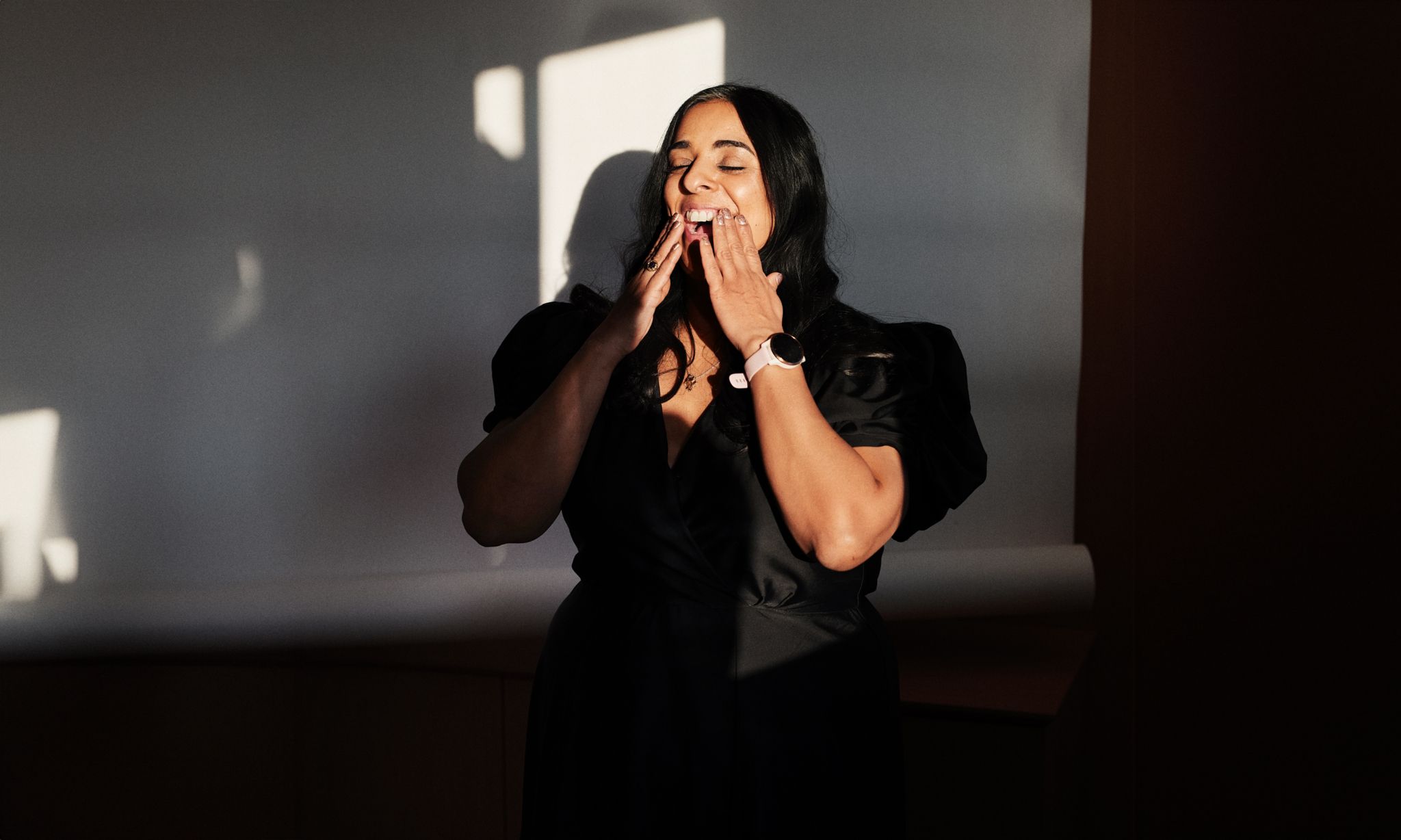 Foto av Lubna i en svart kjole, og hendene opp mot ansiktet.