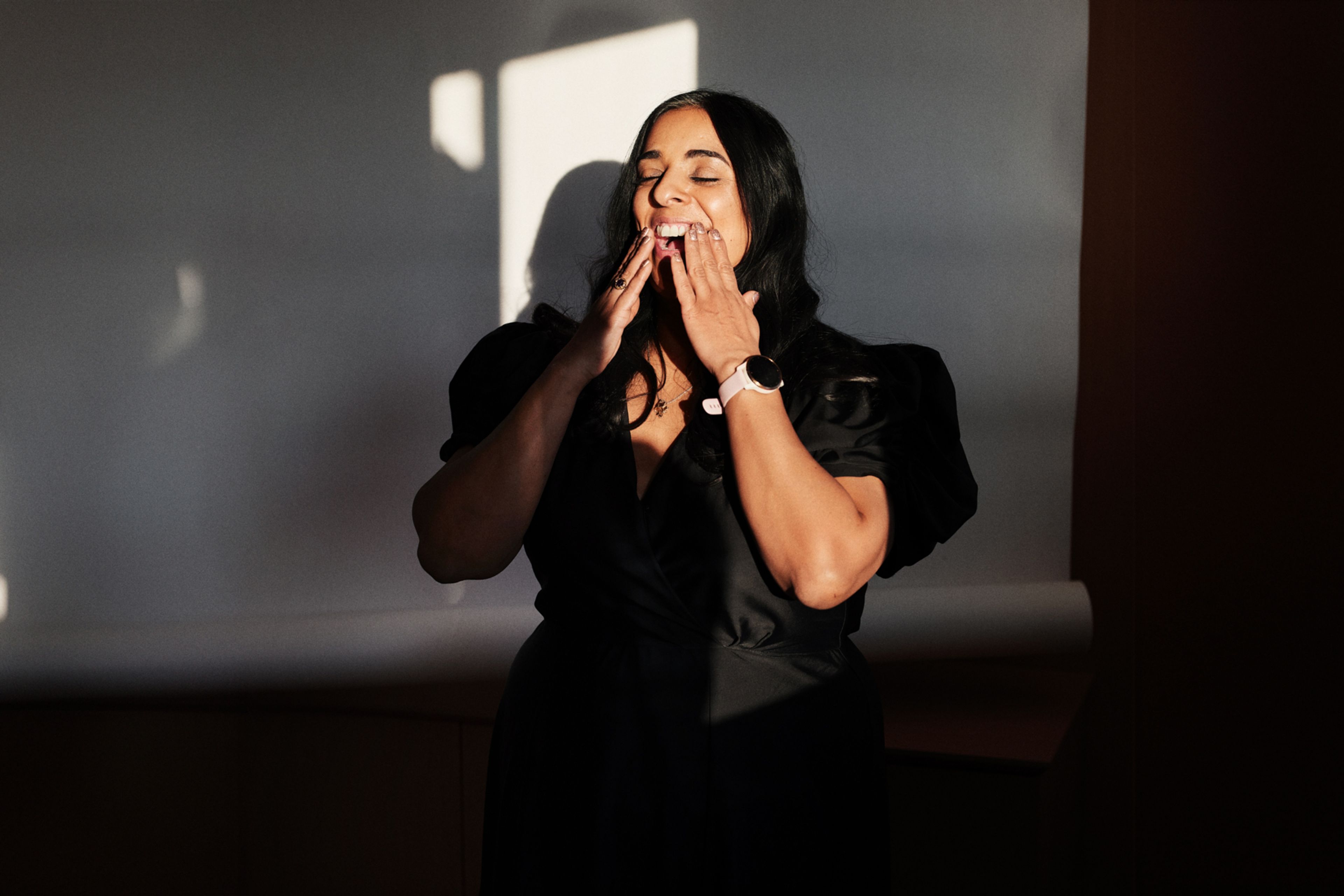 Foto av Lubna i en svart kjole, og hendene opp mot ansiktet.