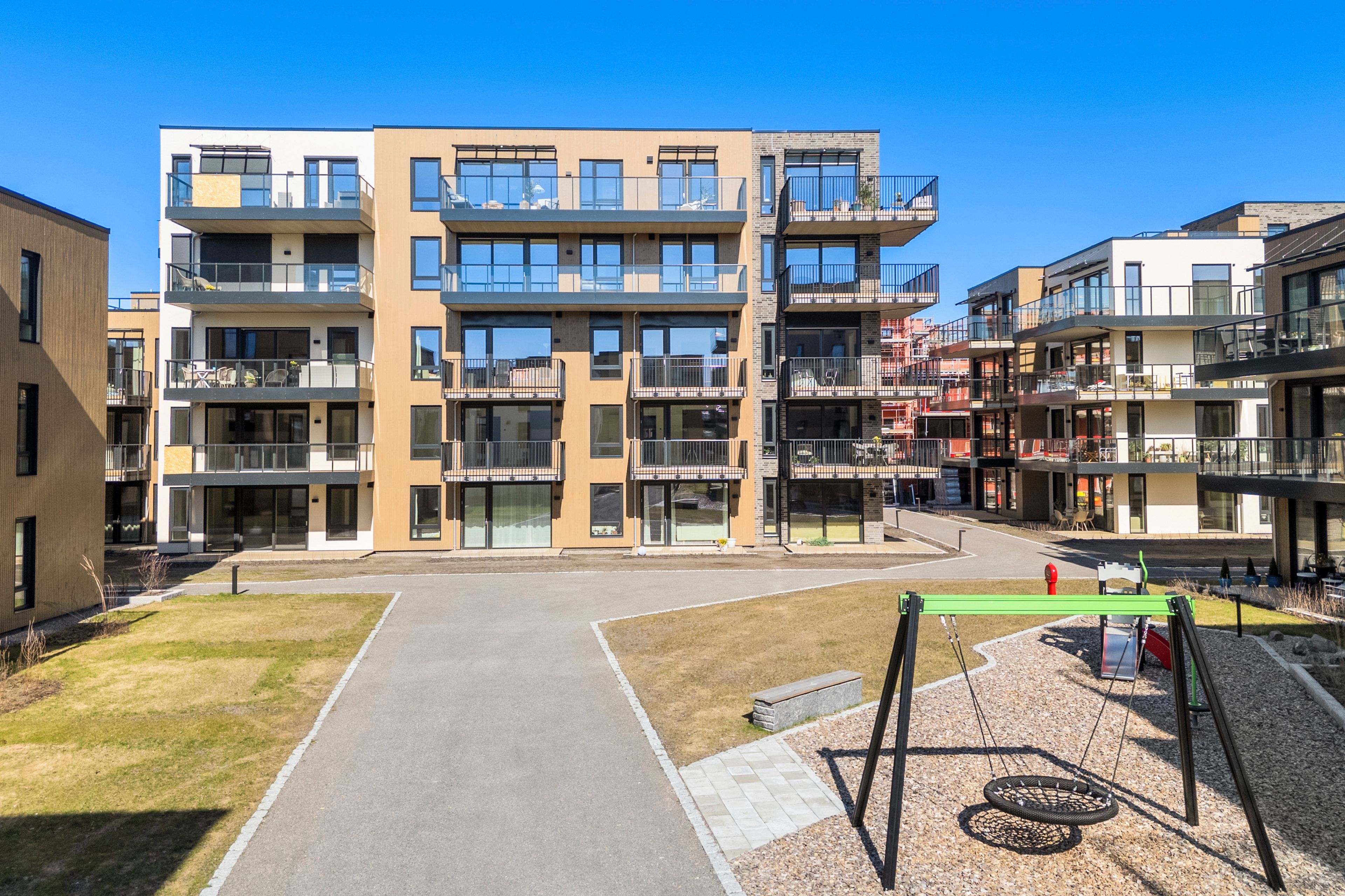 Fasade med balkonger og lekeplass.