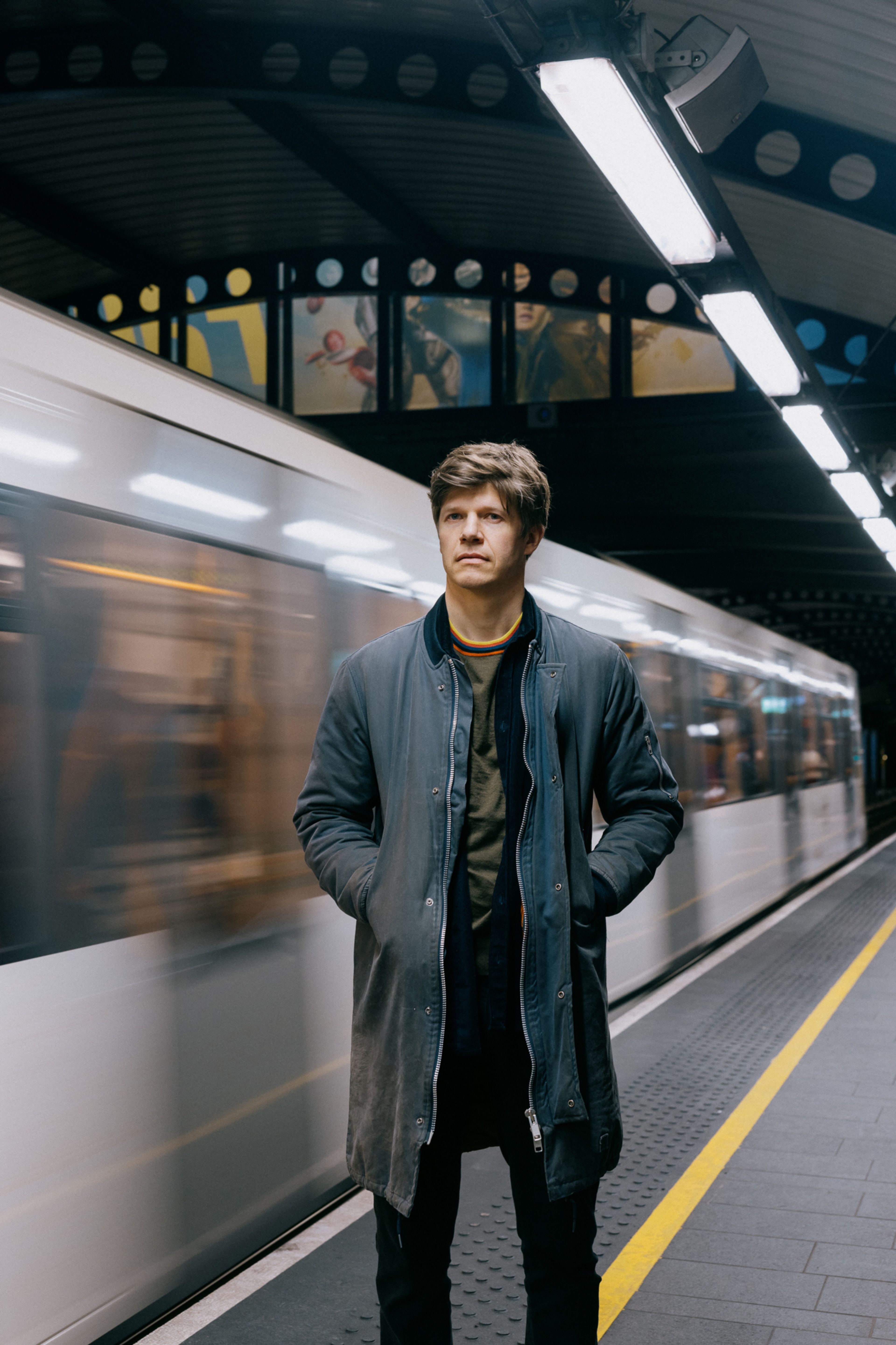 Erlend står utenfor en T-bane i fart på Stortinget stasjon.