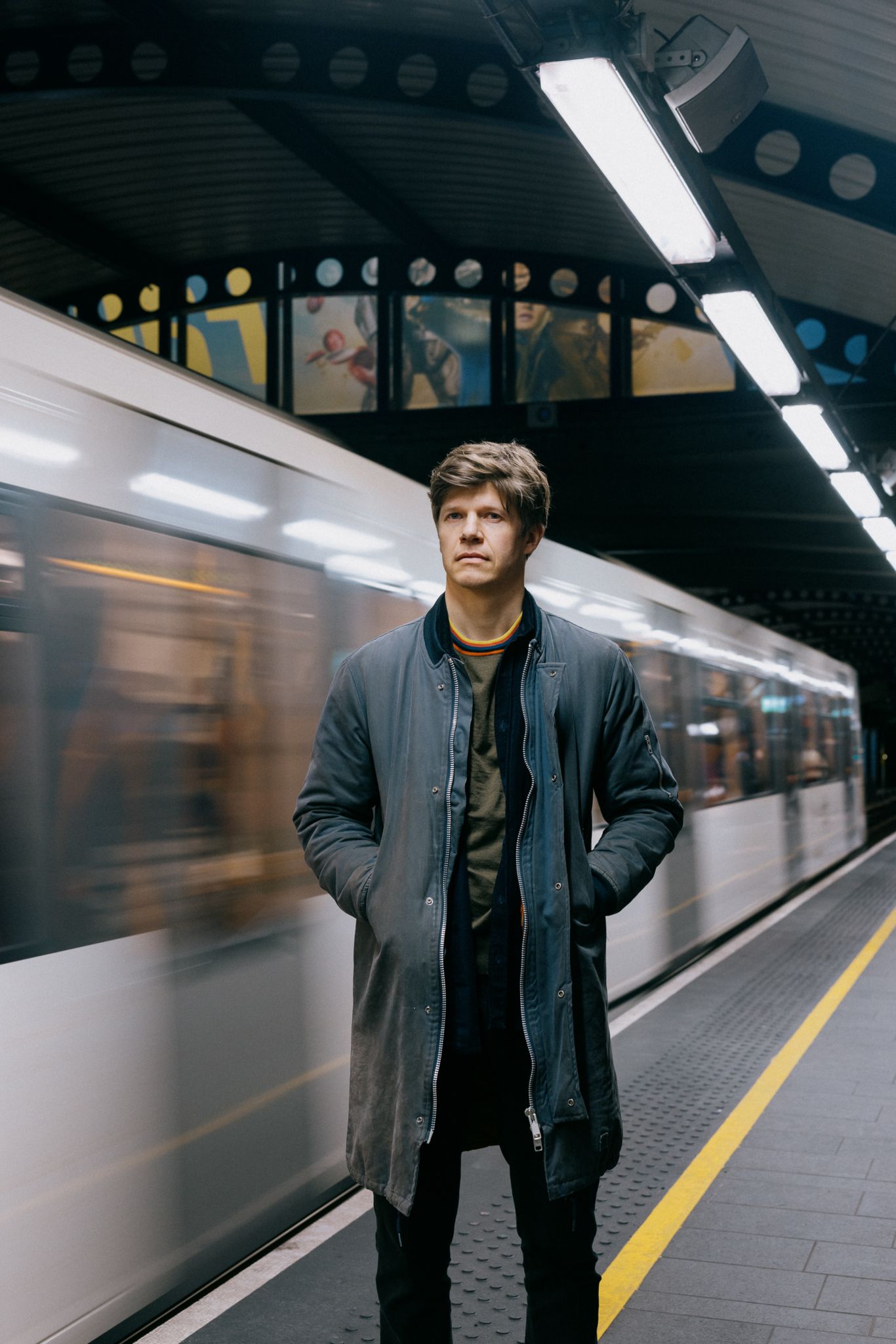 Erlend står utenfor en T-bane i fart på Stortinget stasjon.