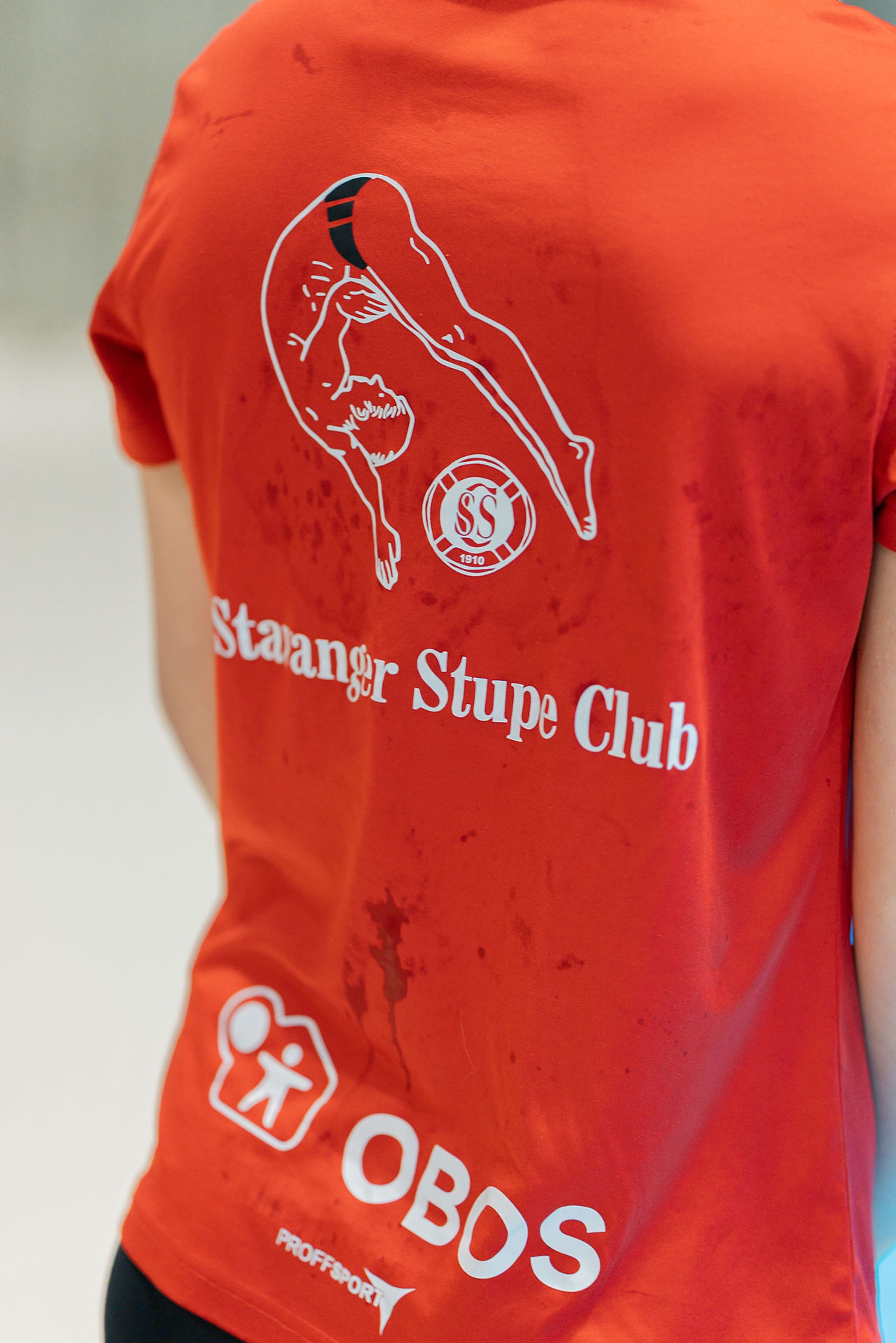 På ryggen av de røde klubb-t-skjortene er logoen til stupeklubben sammen med OBOS logoen.