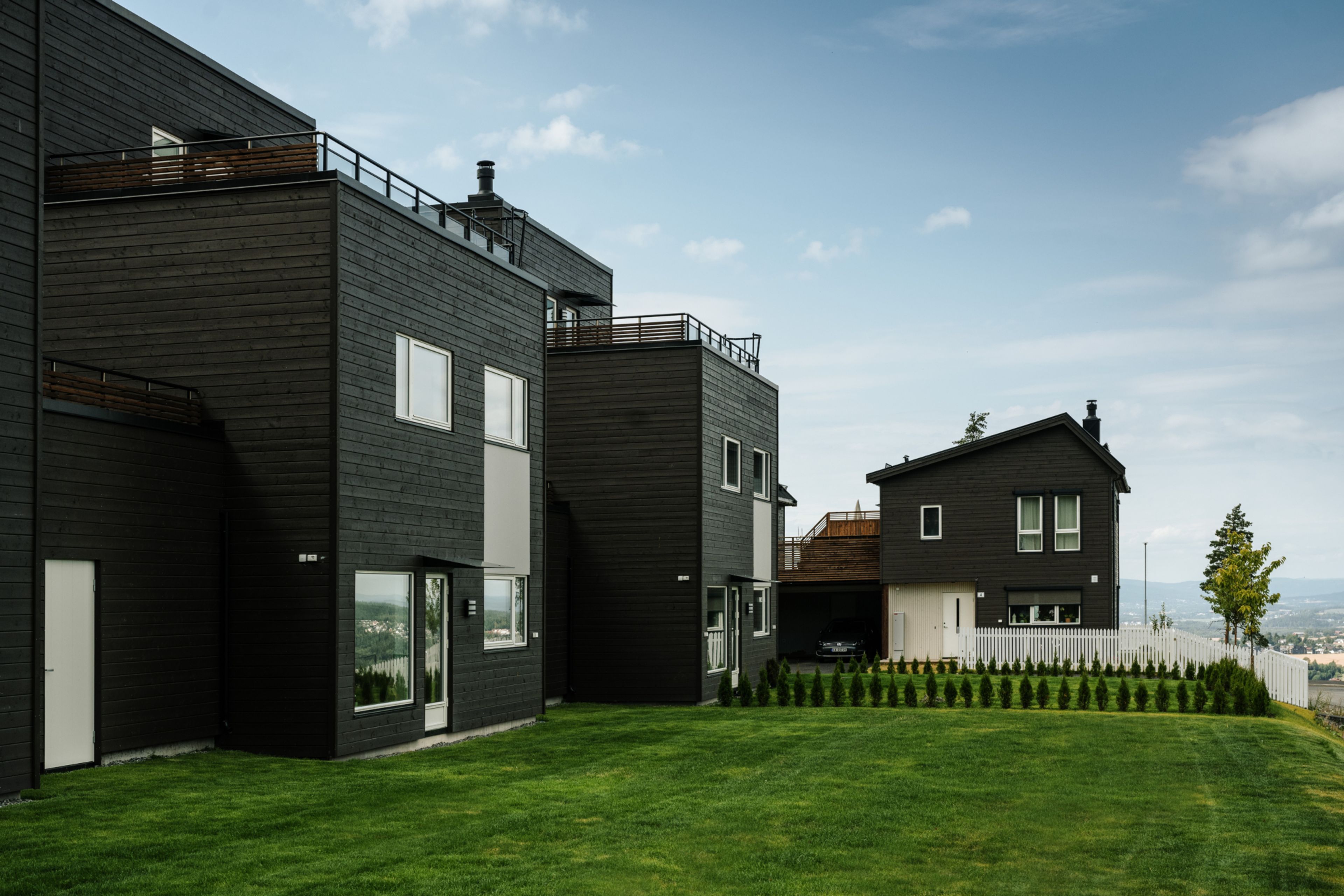 En rekke med OBOS Block Watne-hus i tre, sett fra hagesiden.