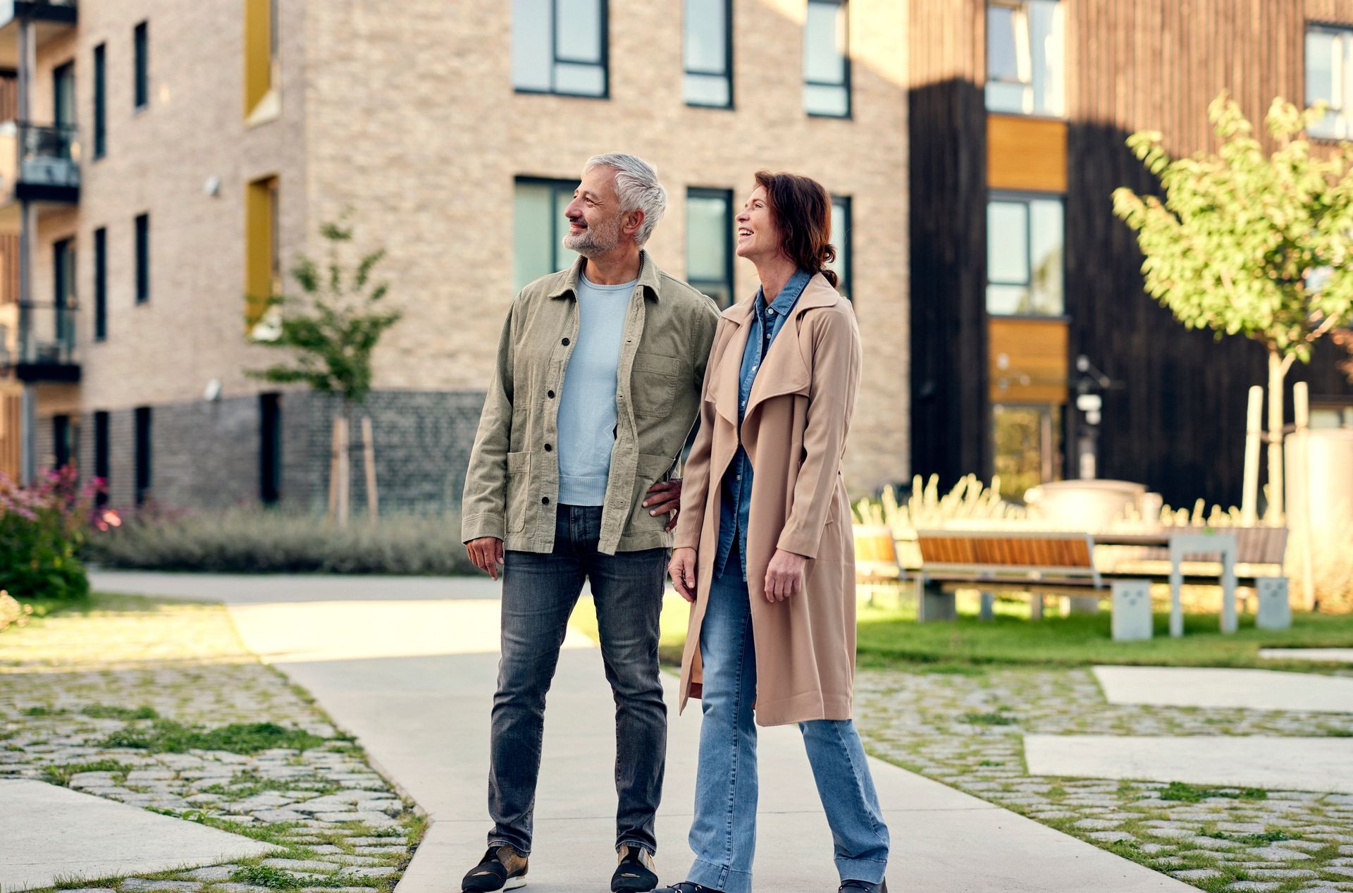 Et par nyter en rolig stund i uteområdet mellom moderne leilighetsbygg.