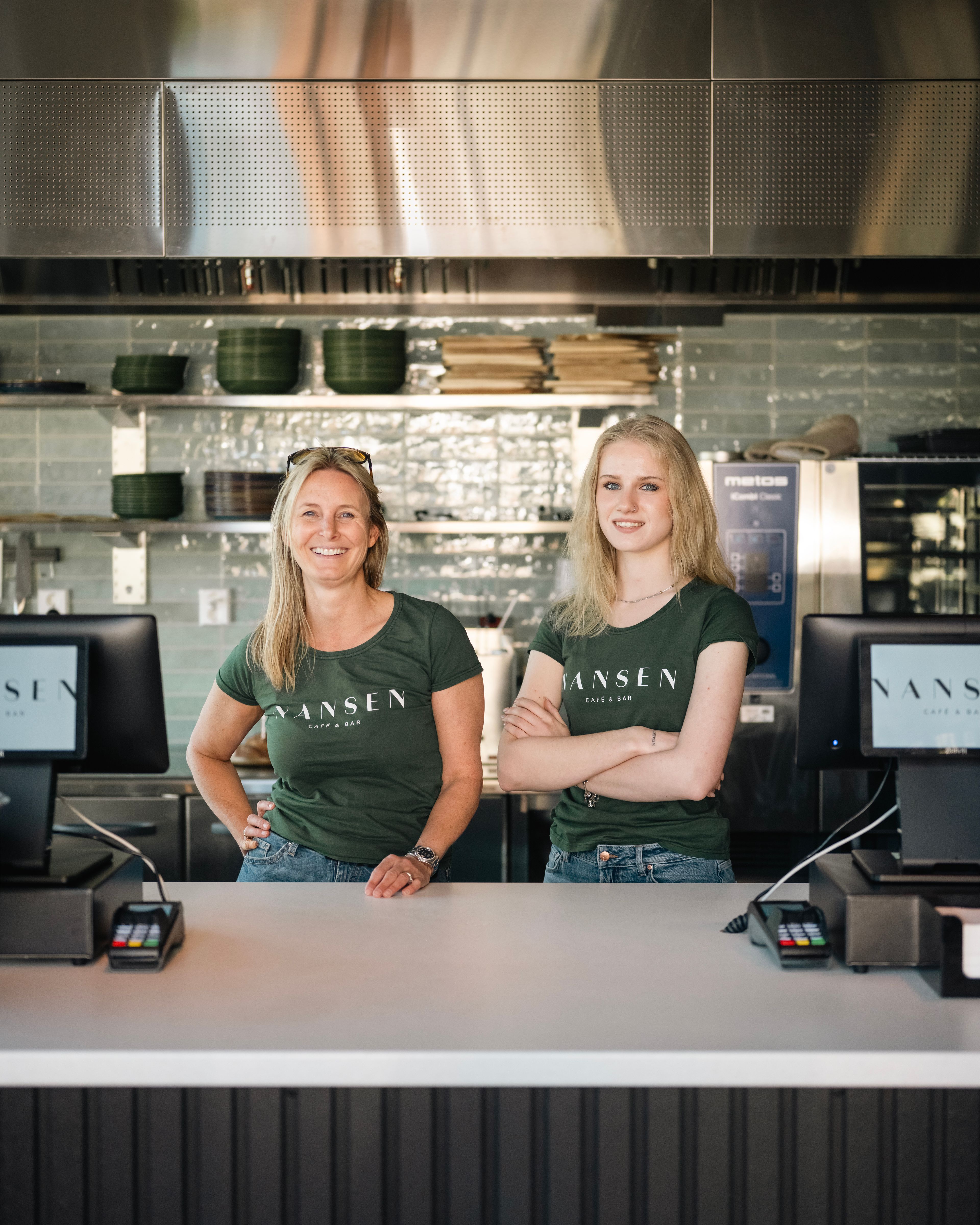 To ansatte smiler bak disken på Nansen Café