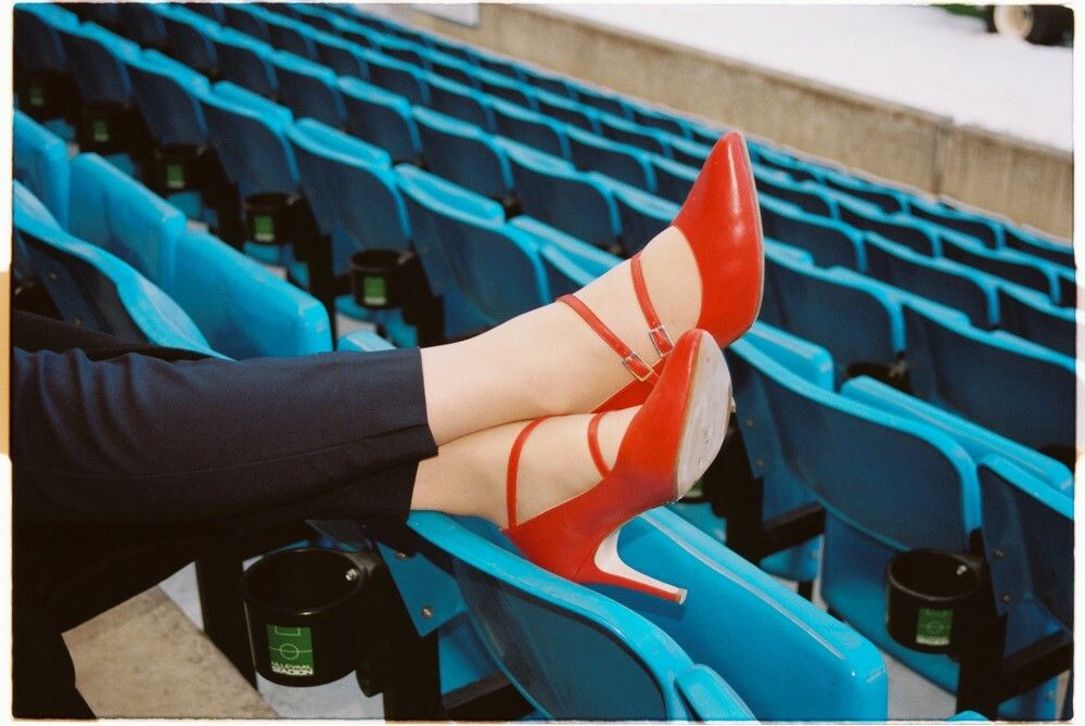 Lise Klaveness hviler beina på tribunesetet med røde pensko på.