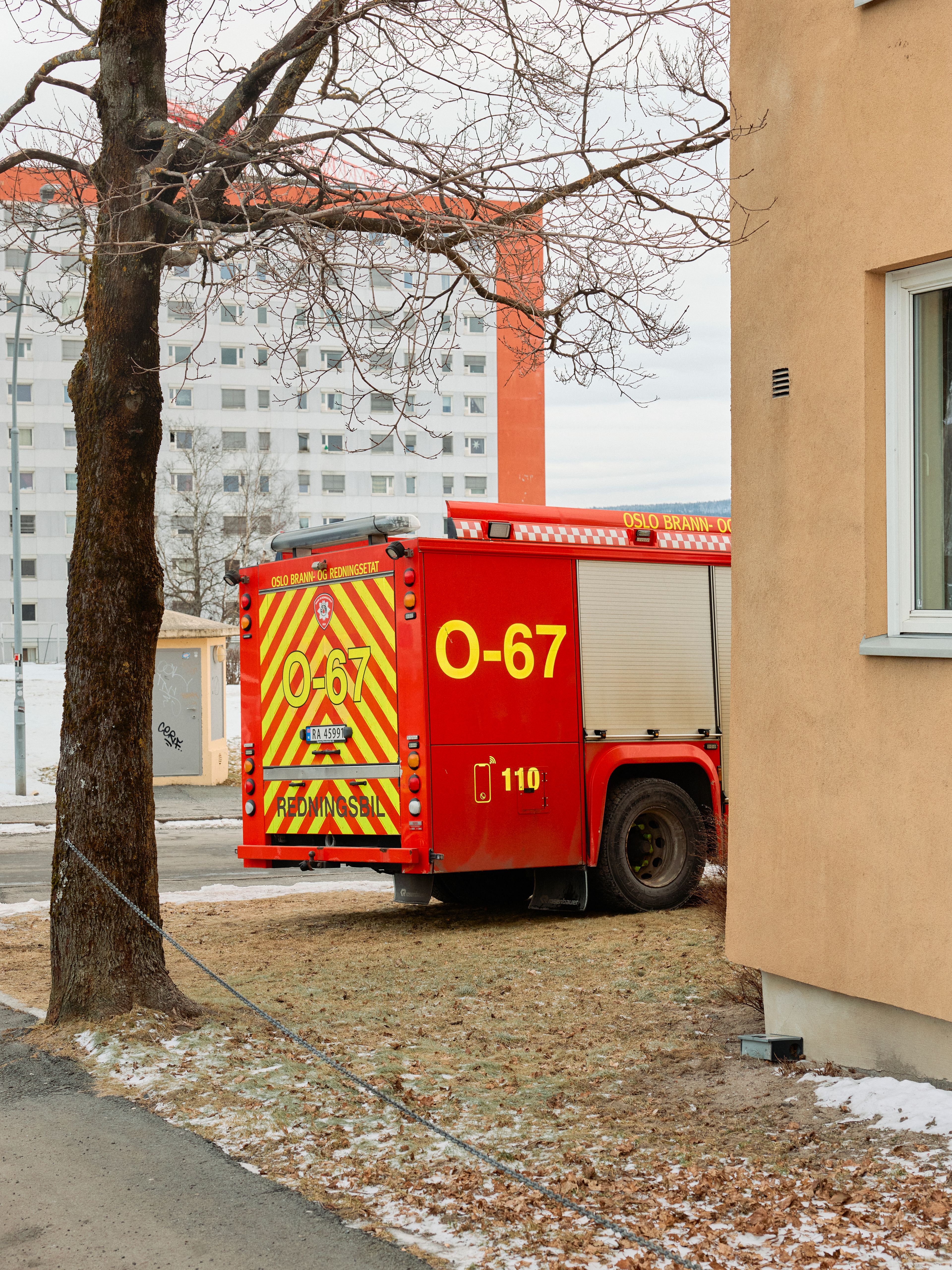 Halvparten av en brannbil bak hushjørnet til et borettslag.
