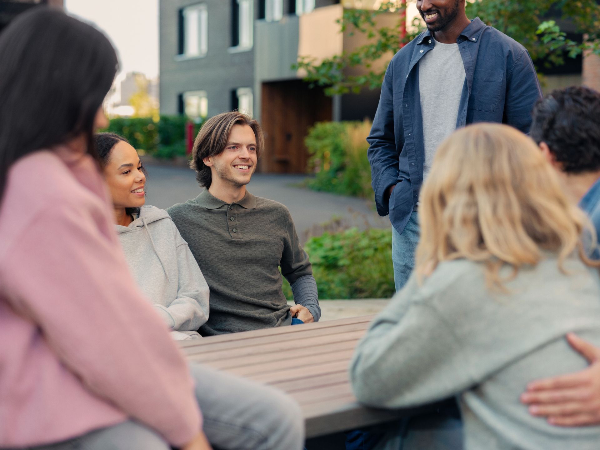 En gruppe beboere sitter ute og snakker sammen i hyggelig lag utenfor boligene sine.