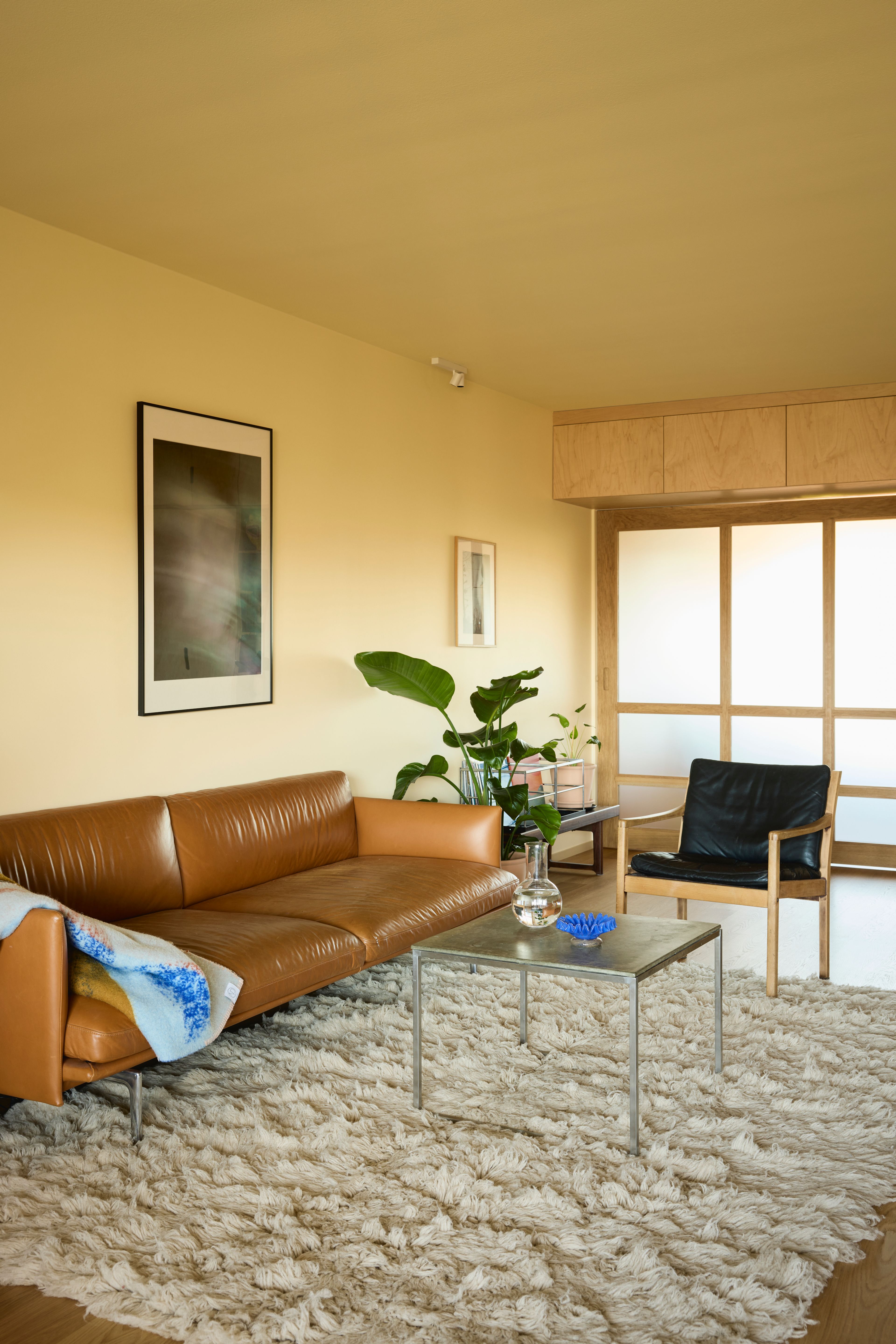 Nærbilde av sofagruppe, sofa i cognacfarget skinn og svart skinnstol.