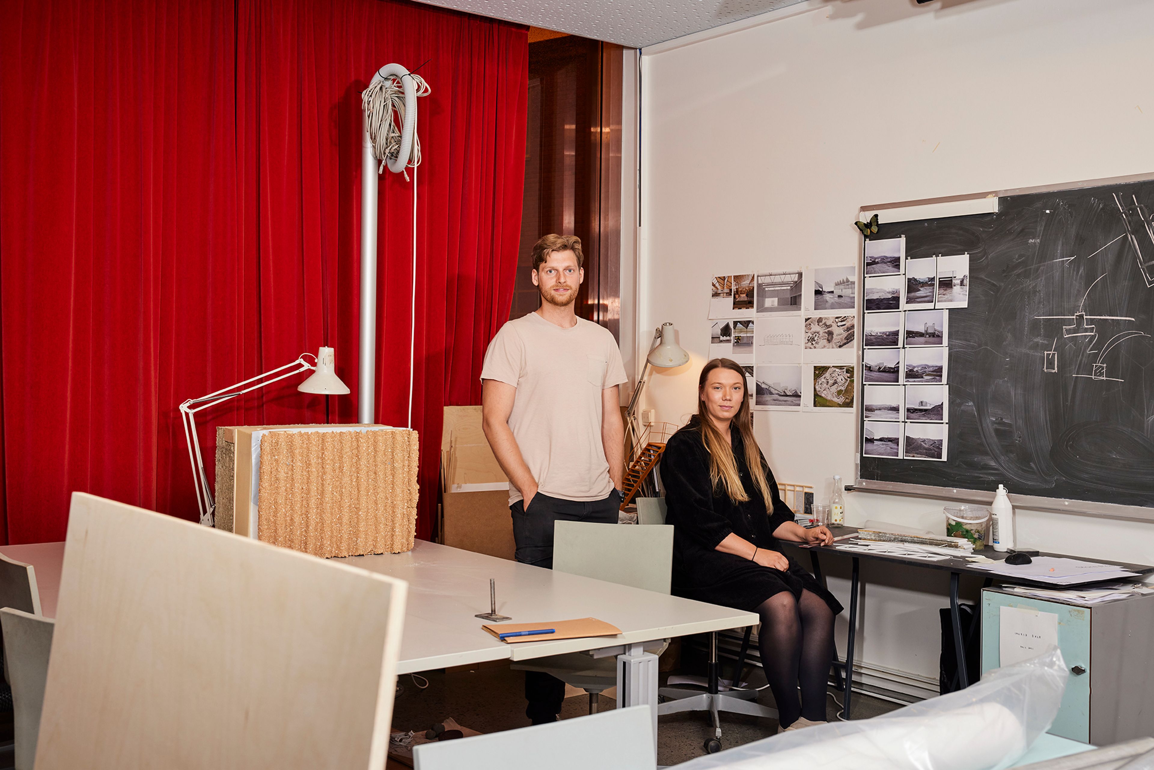 Jonas og Siren i et arbeidsrom på Arkitektur- og design høgskolen i Oslo. Jonas står og Siren sitter ved en pult.