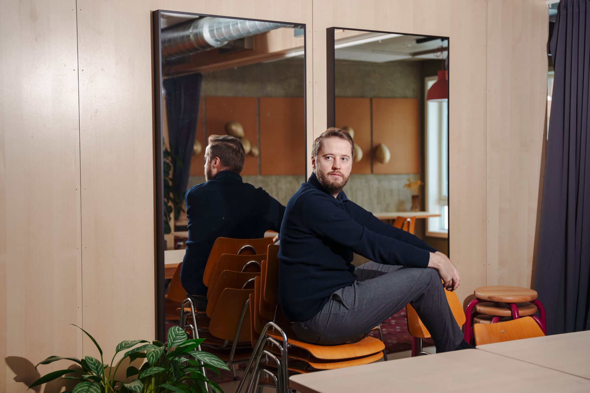 Daglig leder i OBOS Living Lab sitter på en stabel av stoler foran to veggspeil