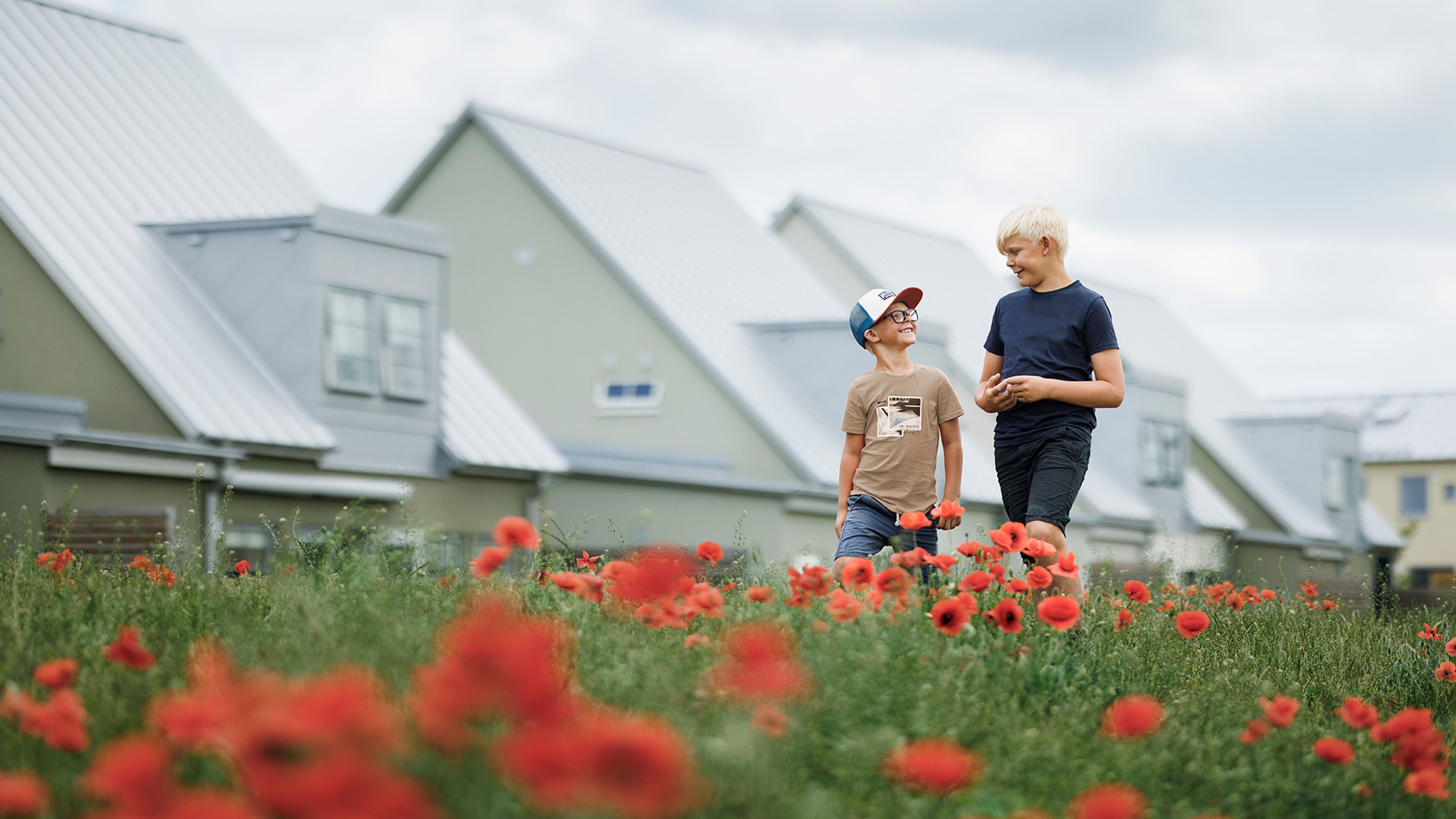 pojkar som går över en äng med hus i bakgrunden