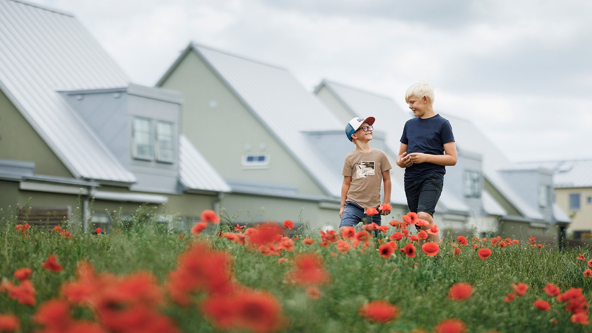 pojkar som går över en äng med hus i bakgrunden