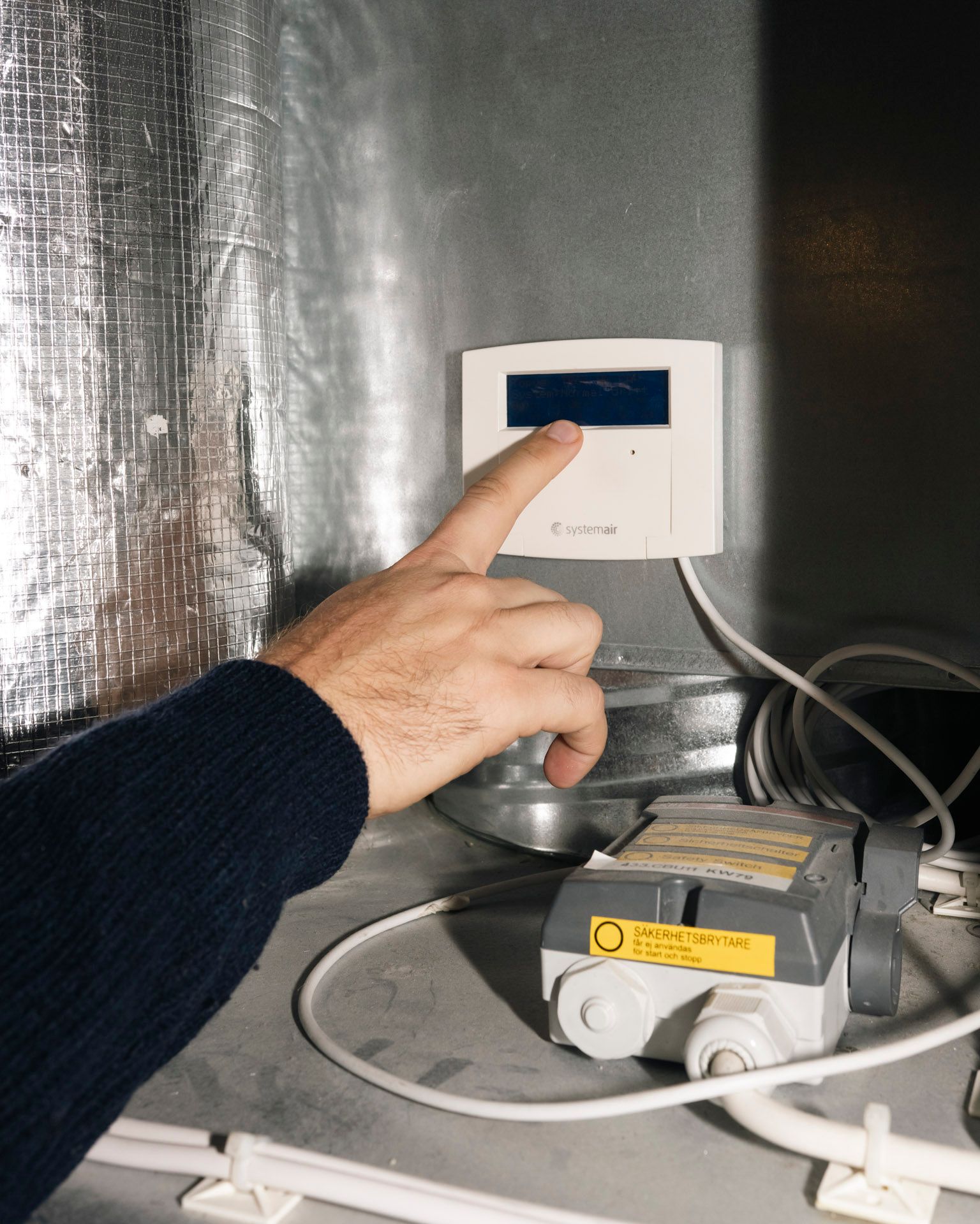 En hånd peker mot temperaturmåler utenfor bod.