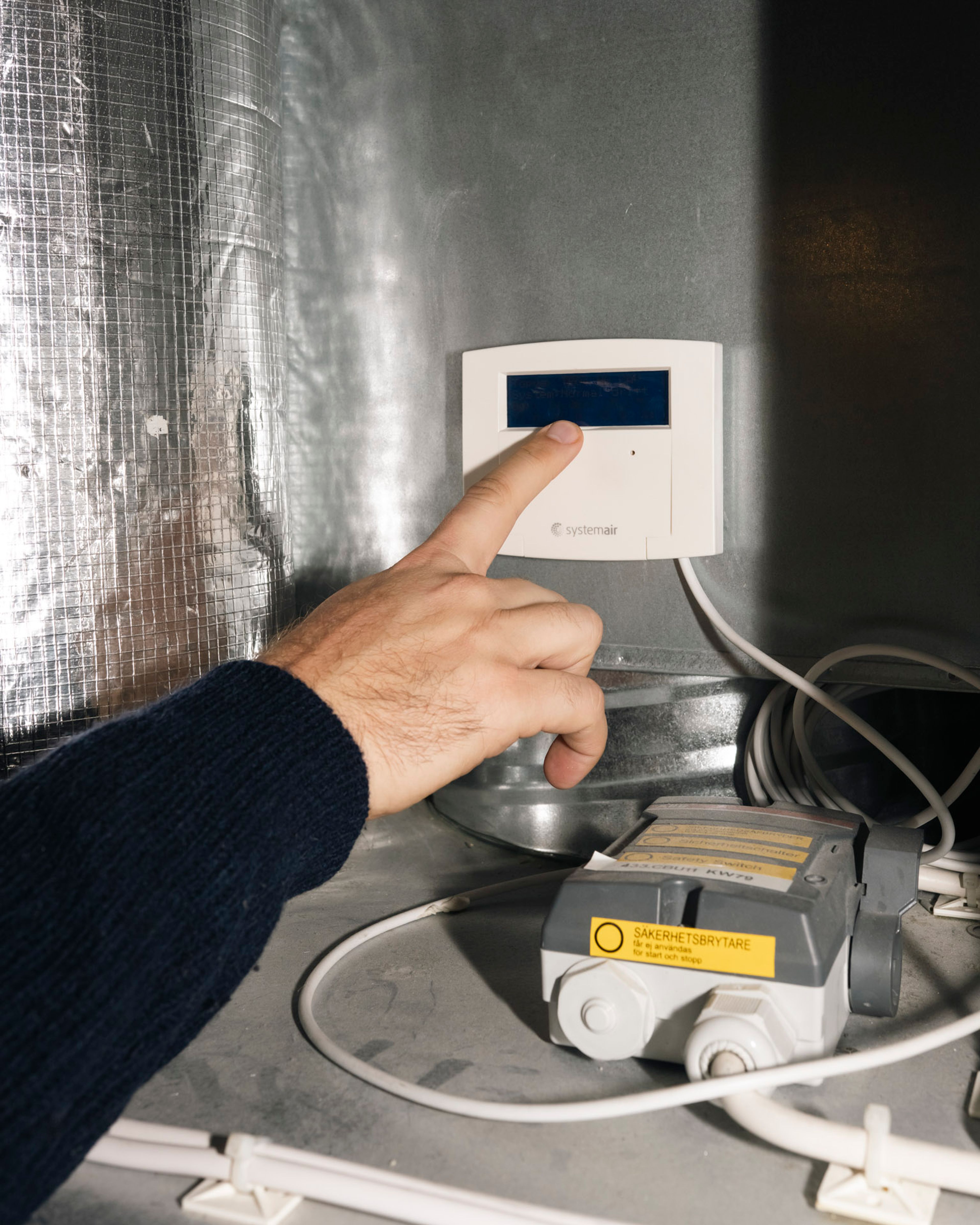 En hånd peker mot temperaturmåler utenfor bod.