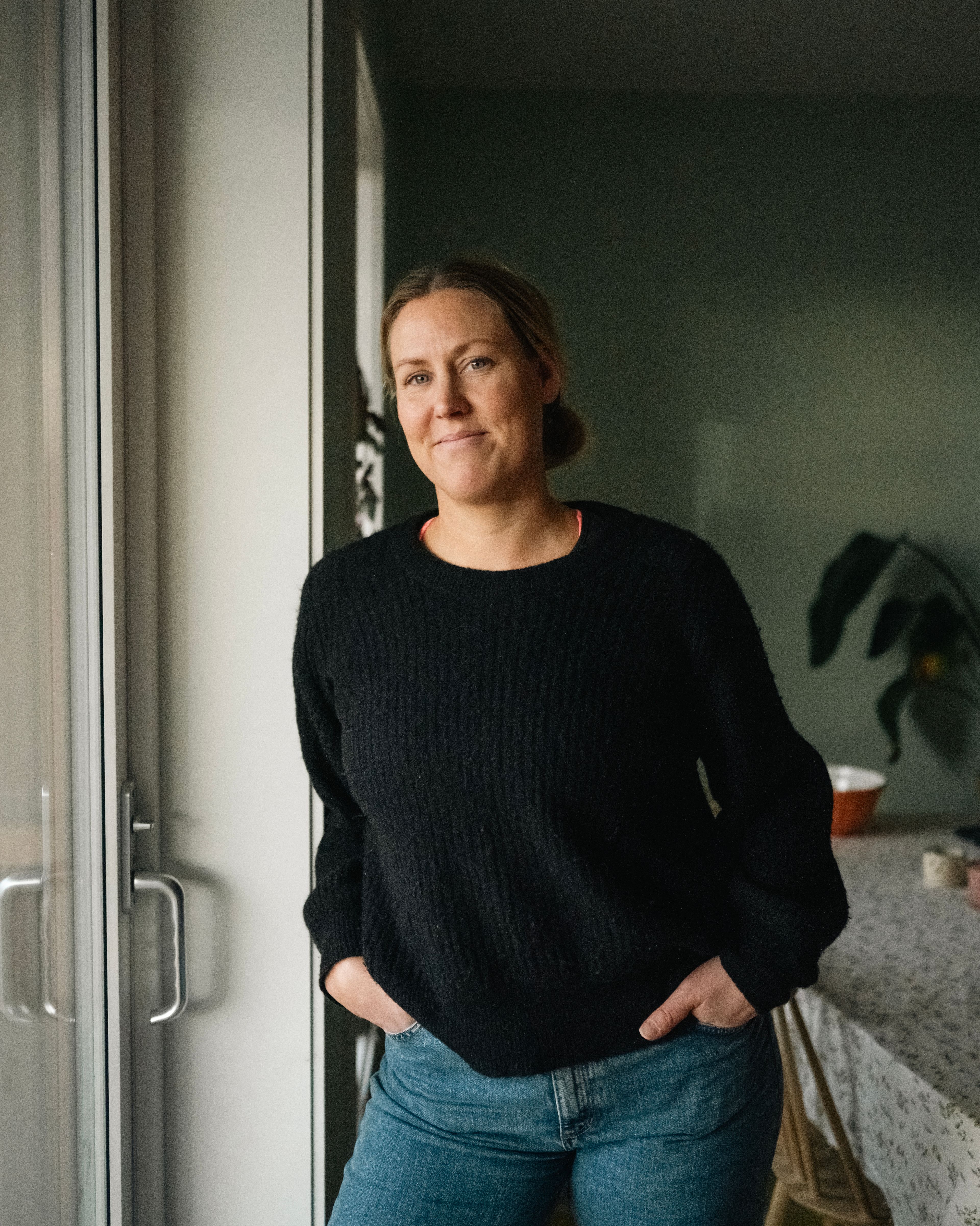 Foto av Kristin stående foran verandadøren i leiligheten på Vollebekk