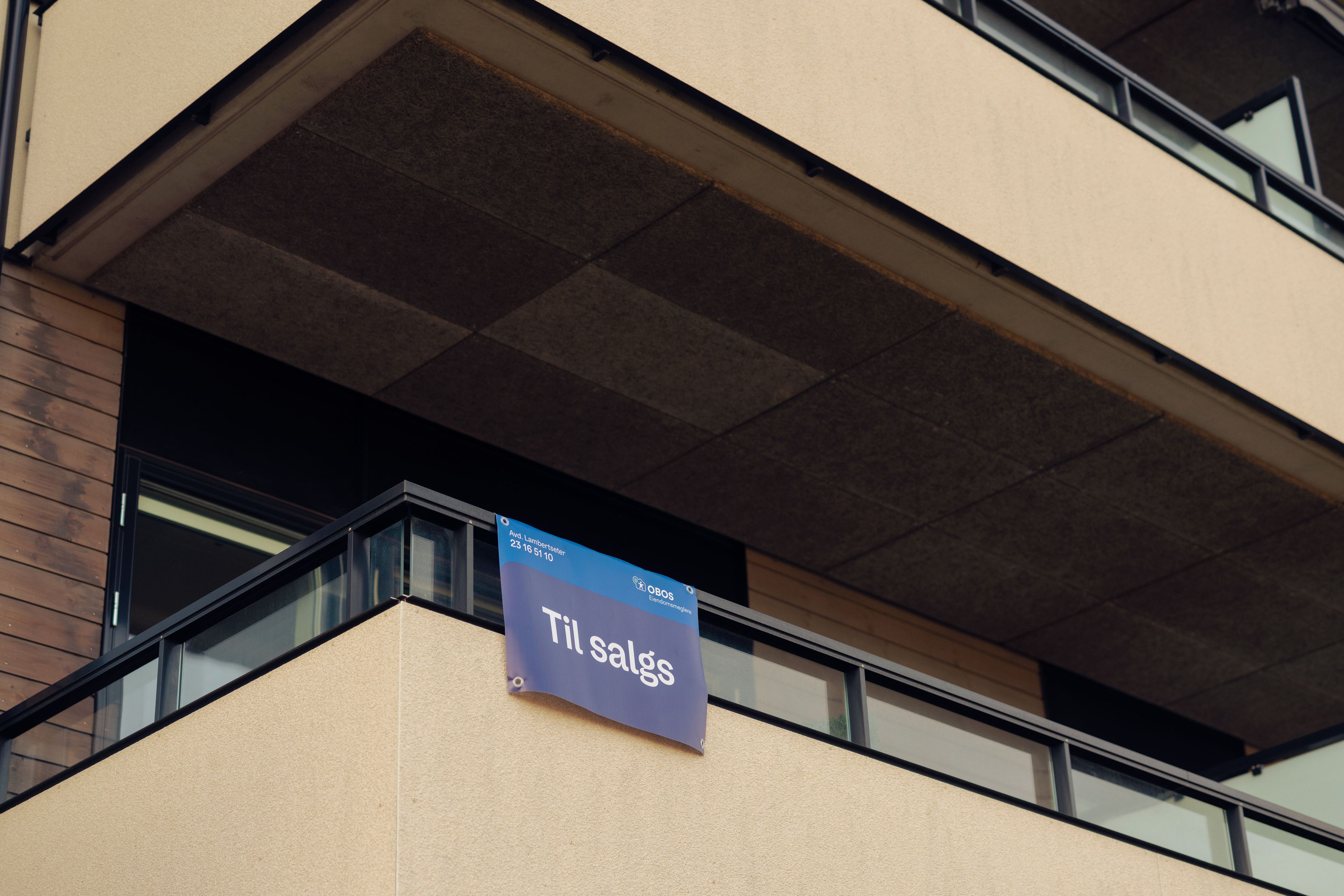 En balkong med et Til salgs-sklt fra OBOS Eiendomsmeglere