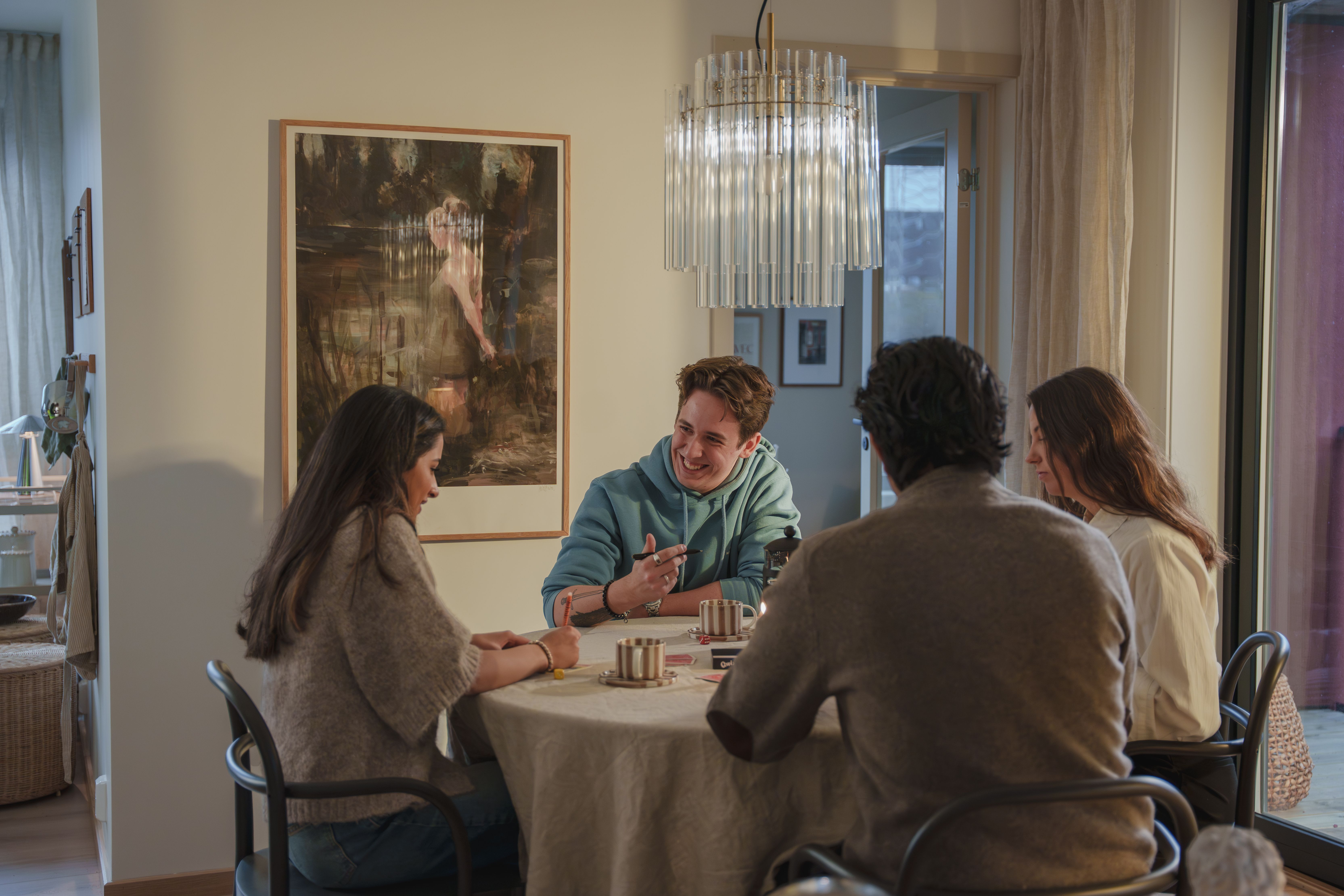 4 unge voksne sitter rundt et bord i OBOS eierkollektiv