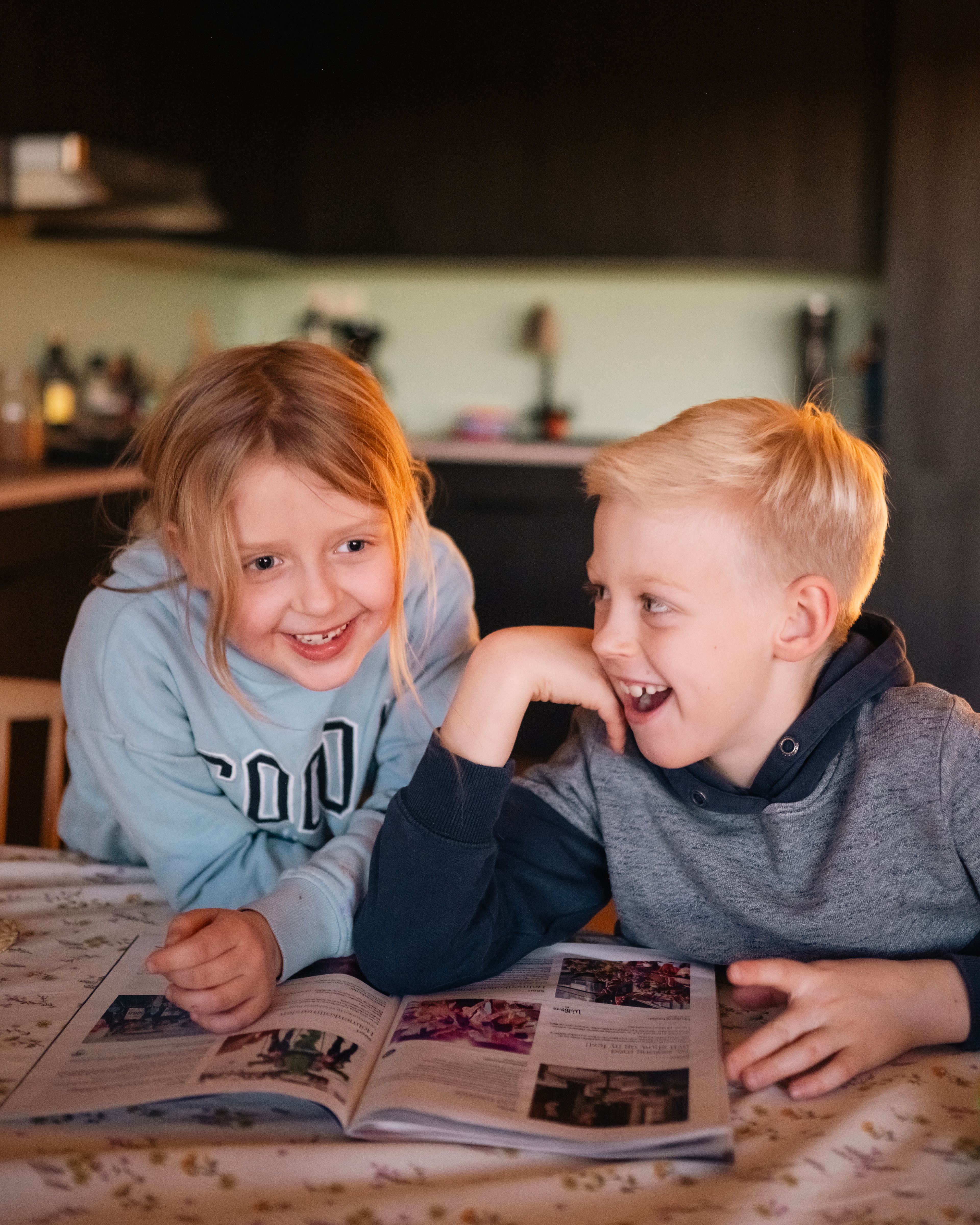 Foto av barna til Kristin som sitter ved spisebordet og blar i et blad