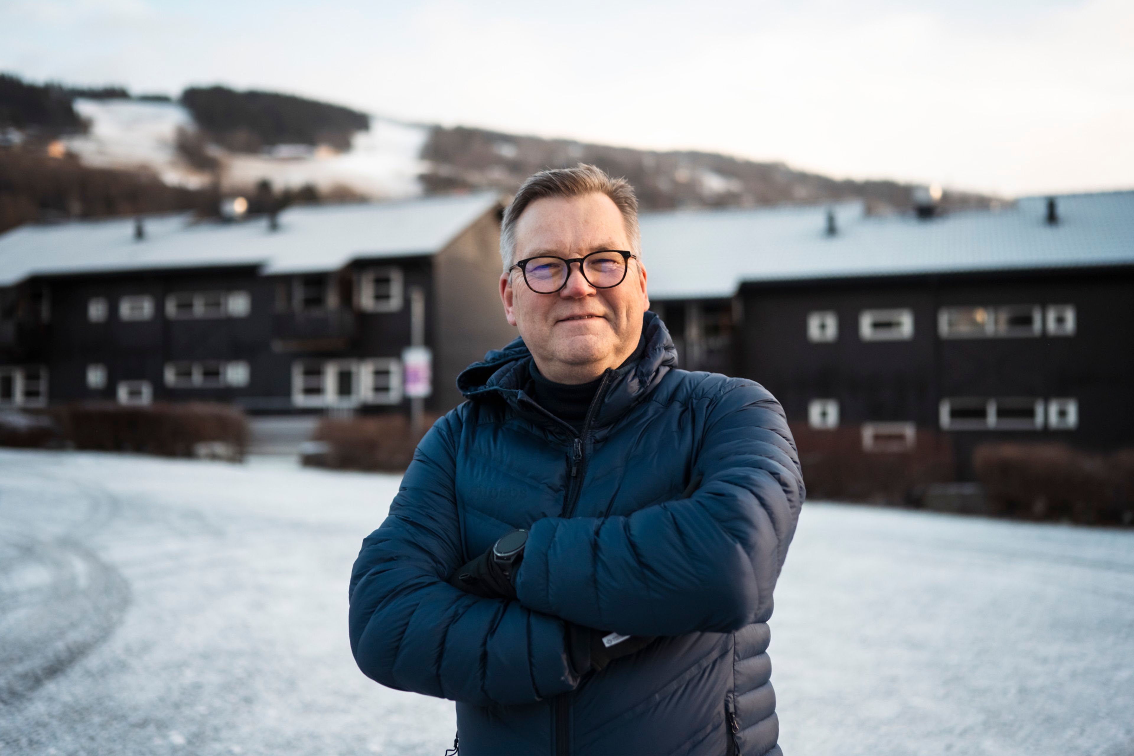 En mann står foran et hyttefelt og ser mot kamera