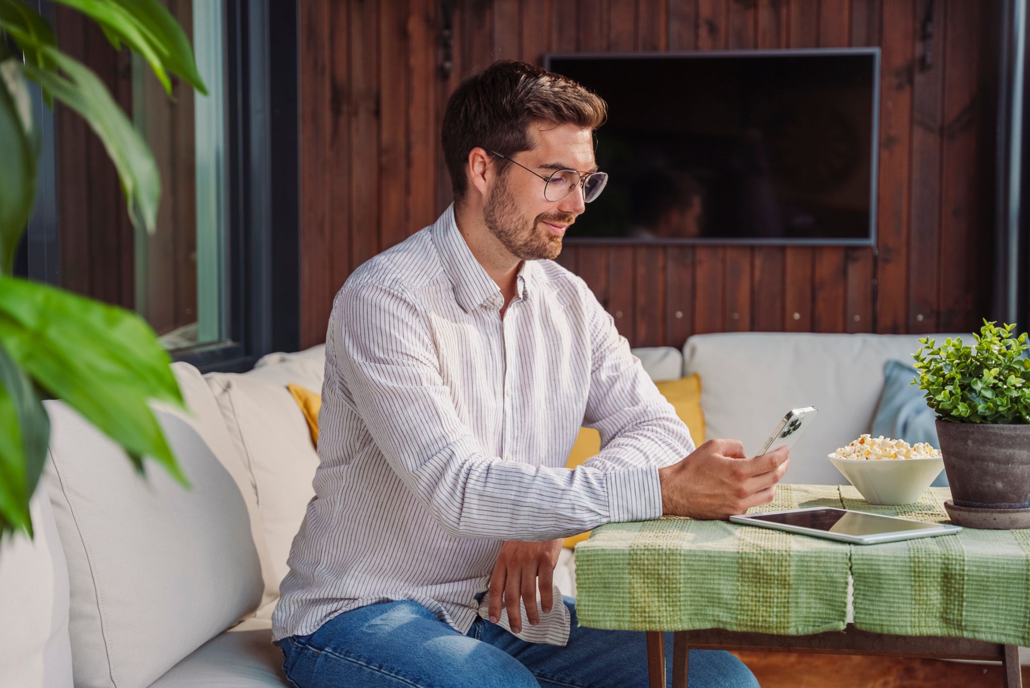 En mann sitter ved et bord og ser på mobilen sin.