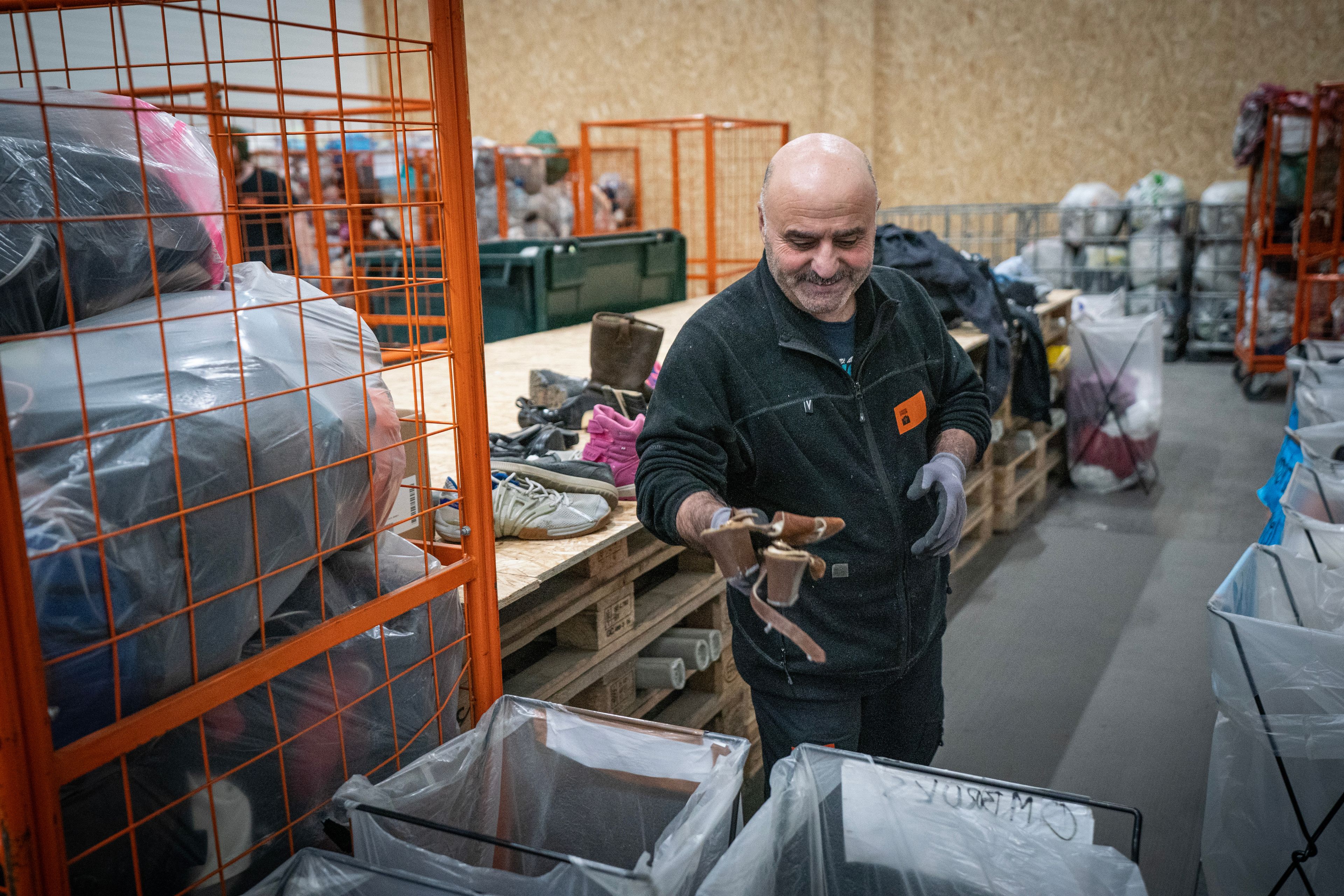 Mann sorterer brukte klær og sko på et mottak hos Kirkens Bymisjon.