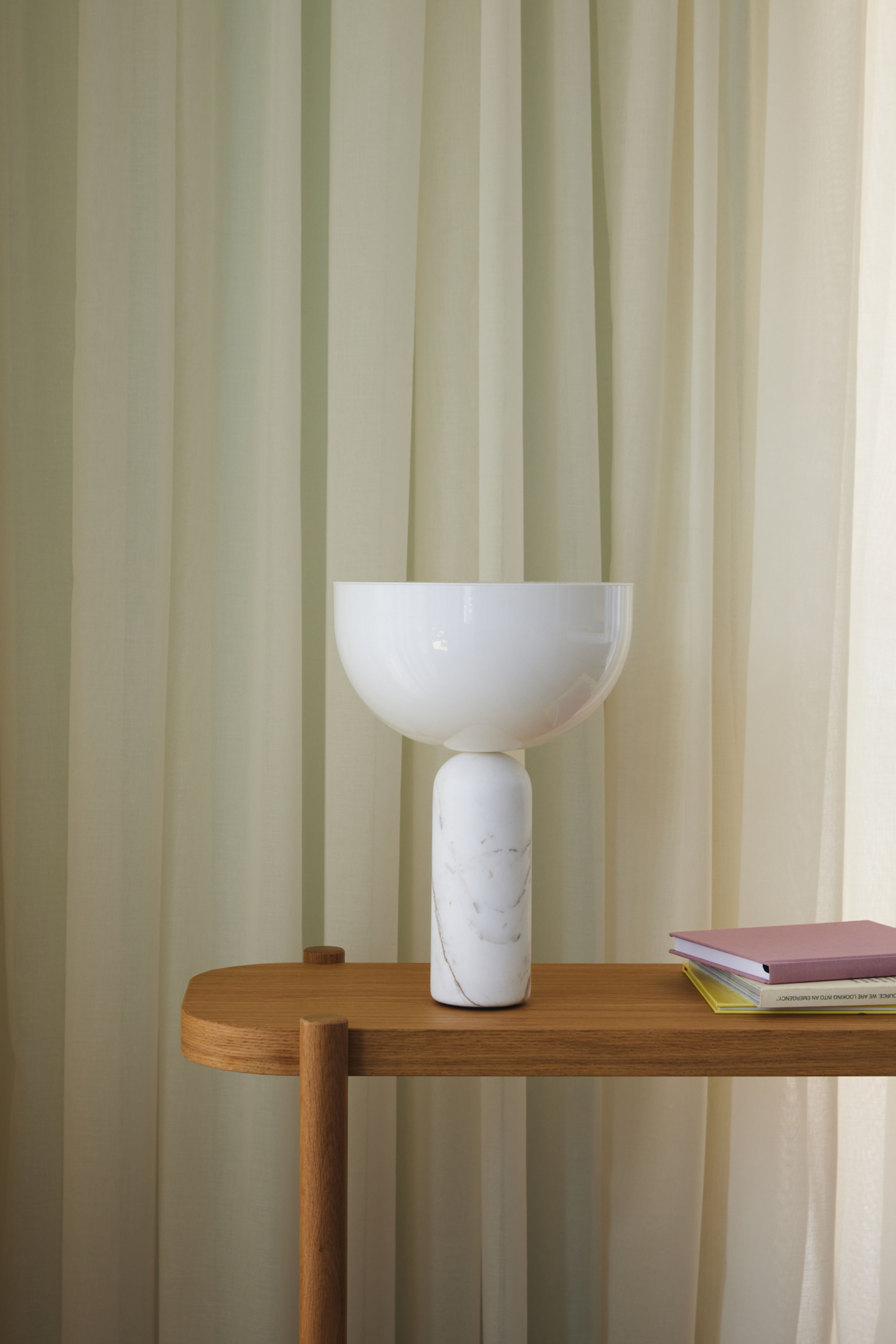 Detaljbilde av en hvit bordlampe og et bord i eik