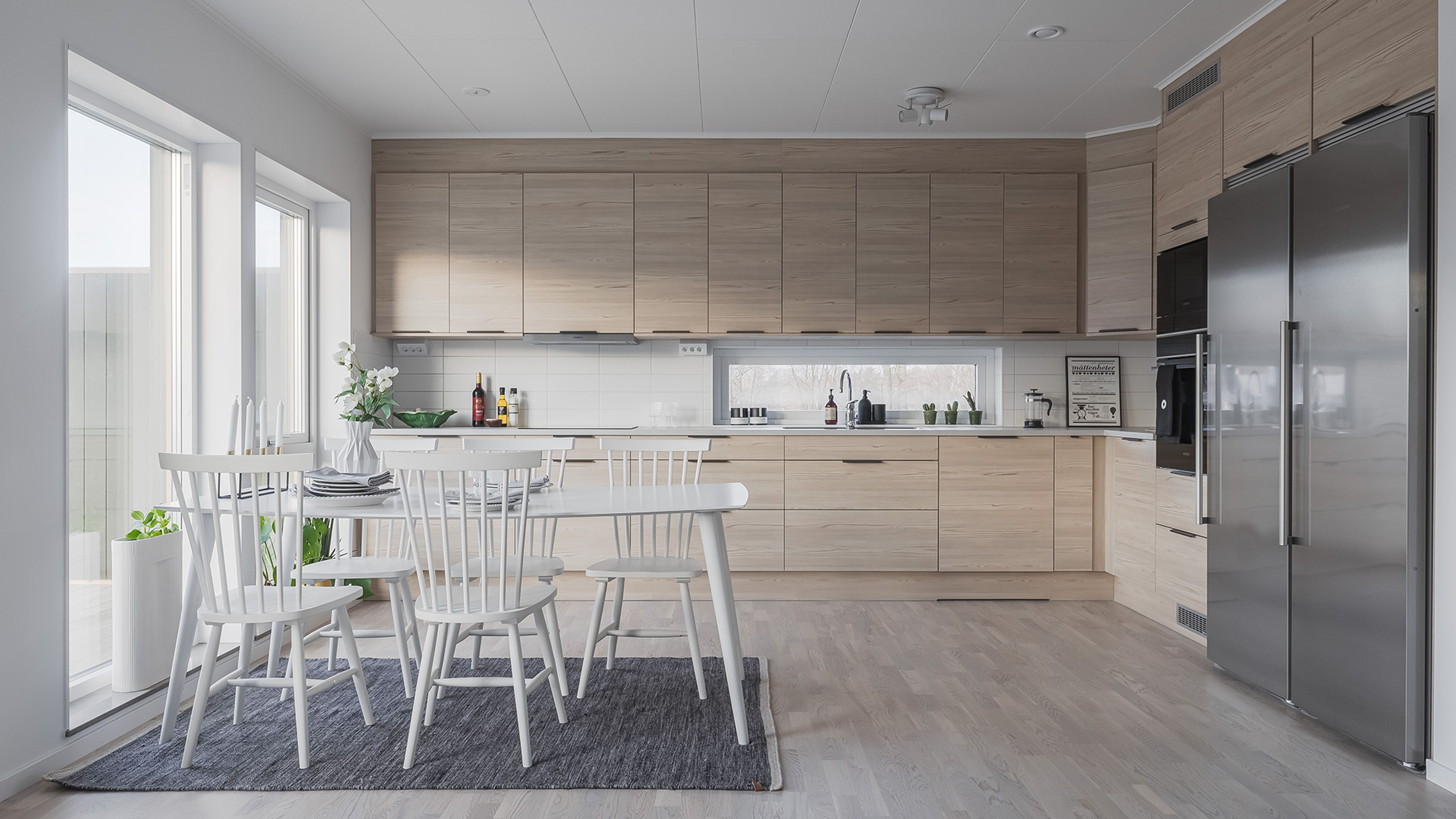 Kök i naturfärger med vitt köksbord och vitvaror i aluminium