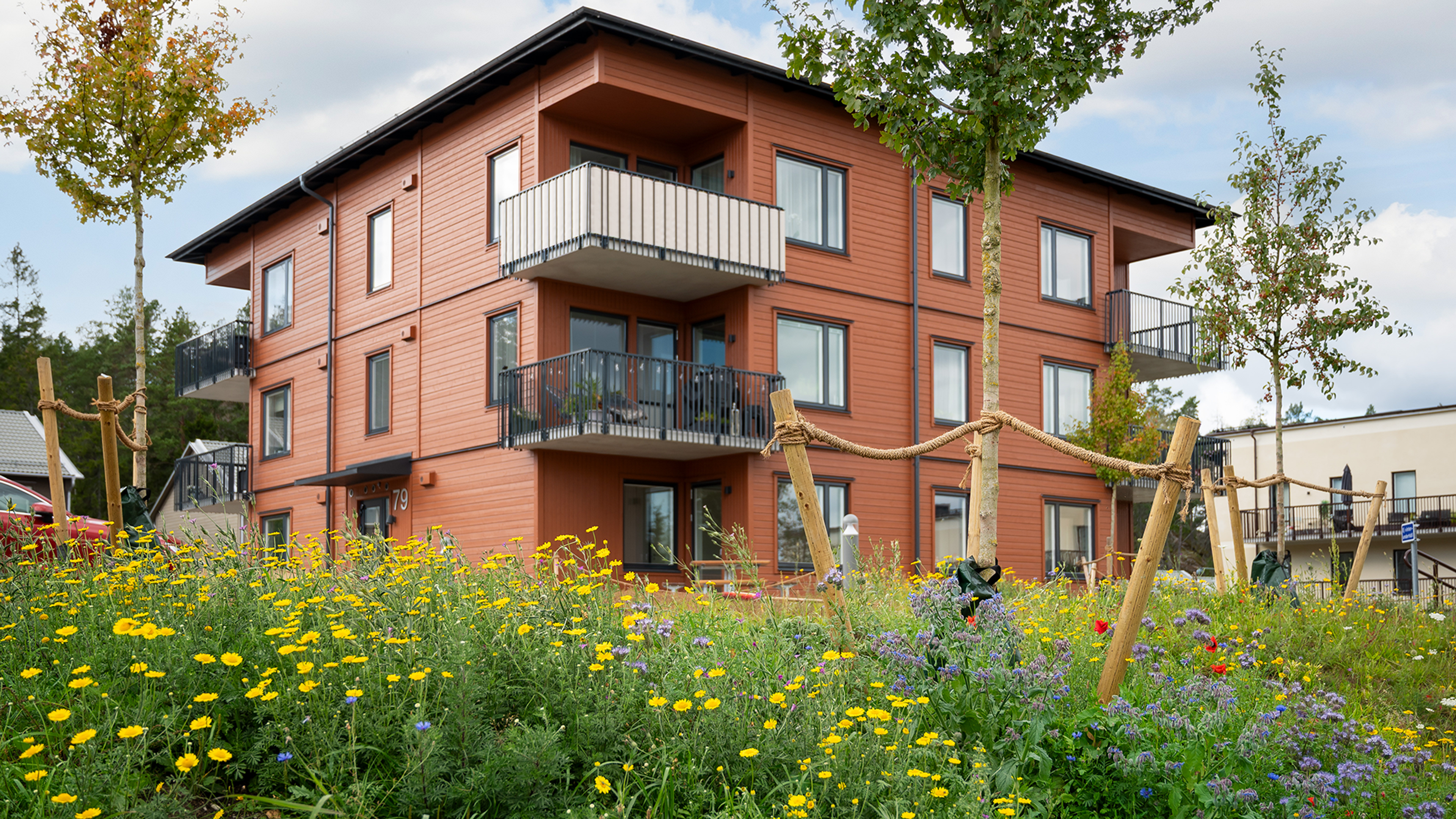 Orange 3-våningshus i Brf Vega Garden med blomster i förgrunden