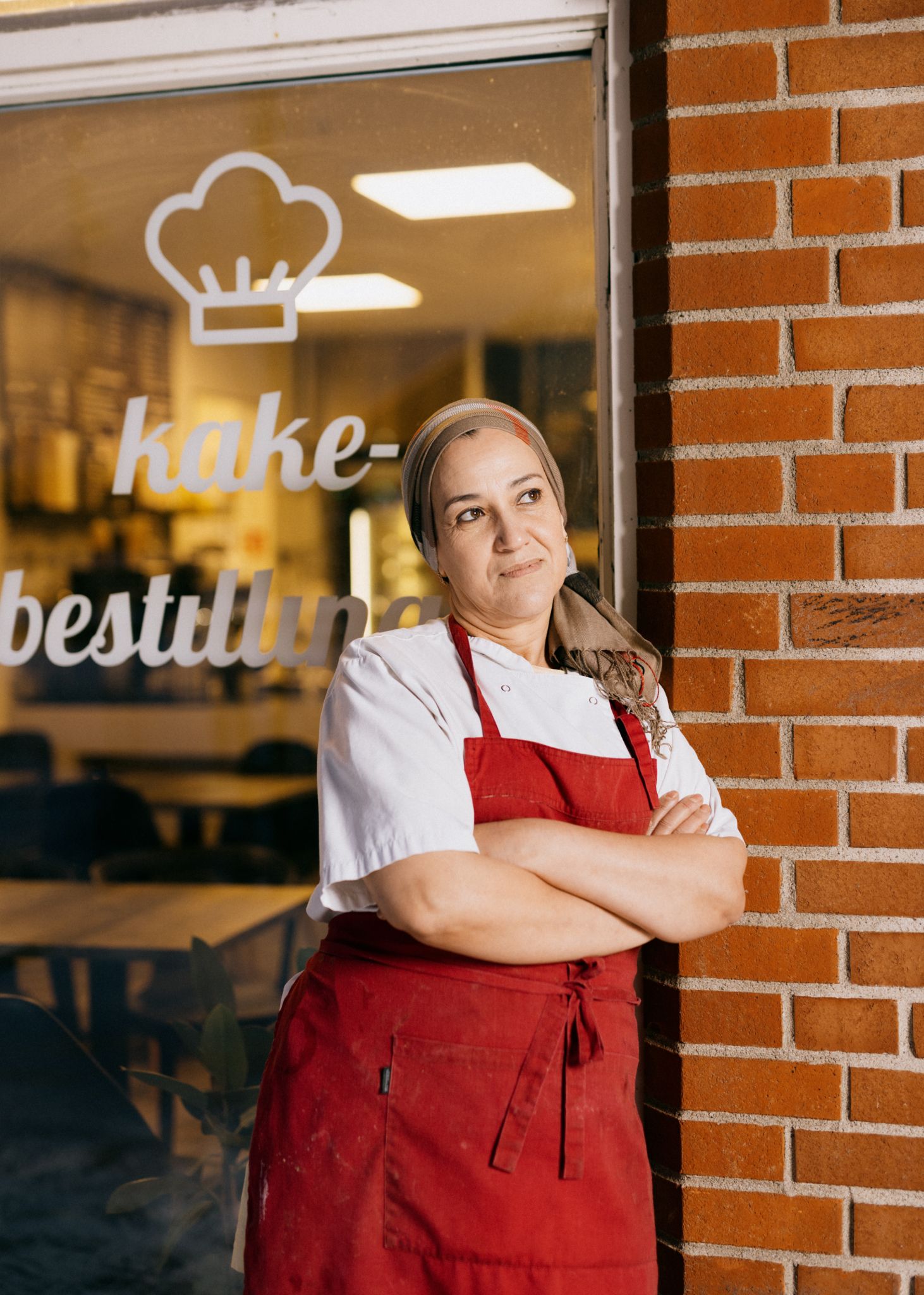 Foto av Nayat Abbouz som står utenfor Kulturkafeen med armene i kort og ser skrått, opp mot himmelen