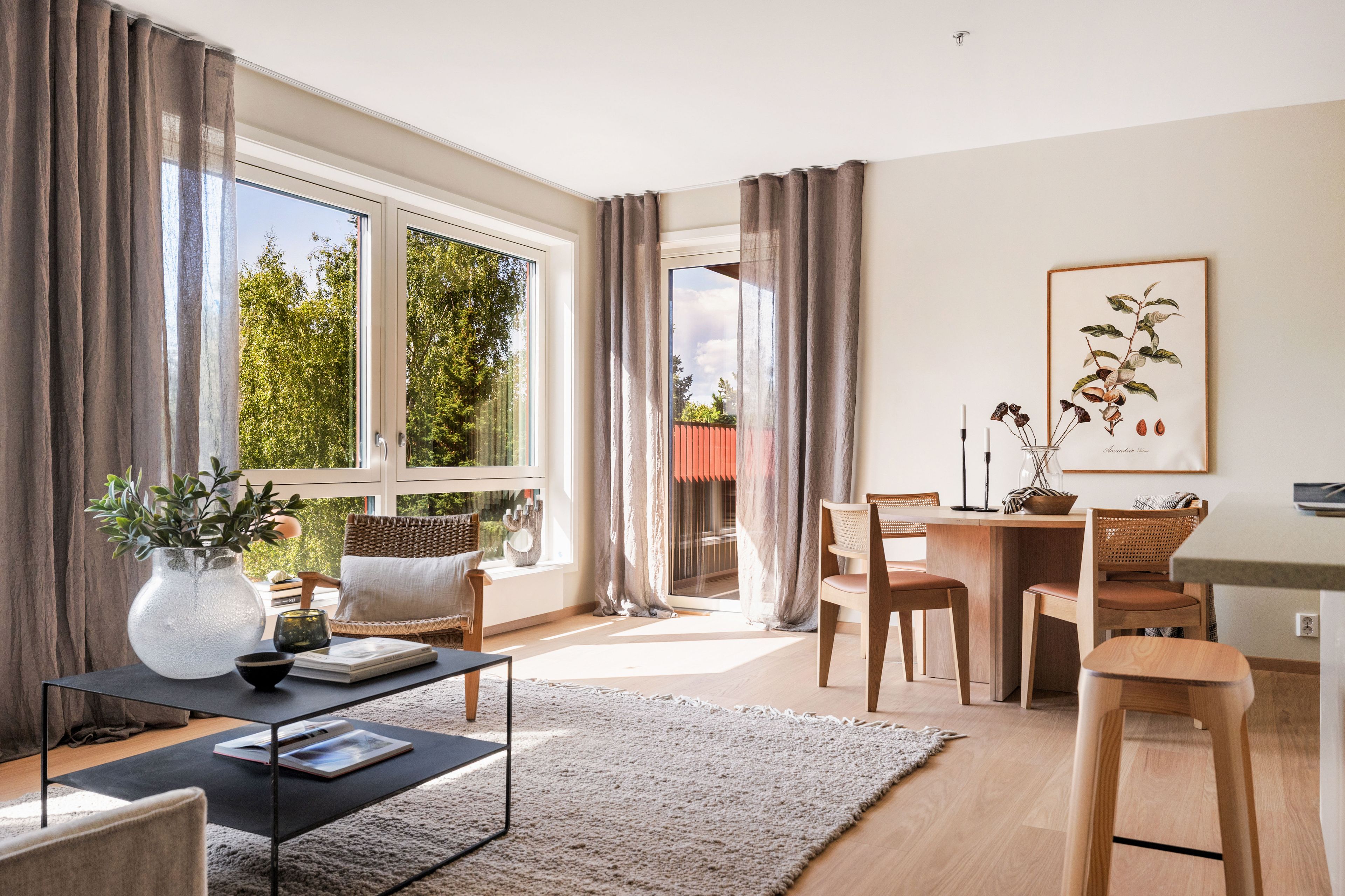Foto av stua. Det er store vinduer som slipper inn rikelig med naturlig lys. Stua er dekorert med sofa, godstol og spisebord. Bildegalleriet inneholder illustrasjonsbilder. Avvik kan forekomme.