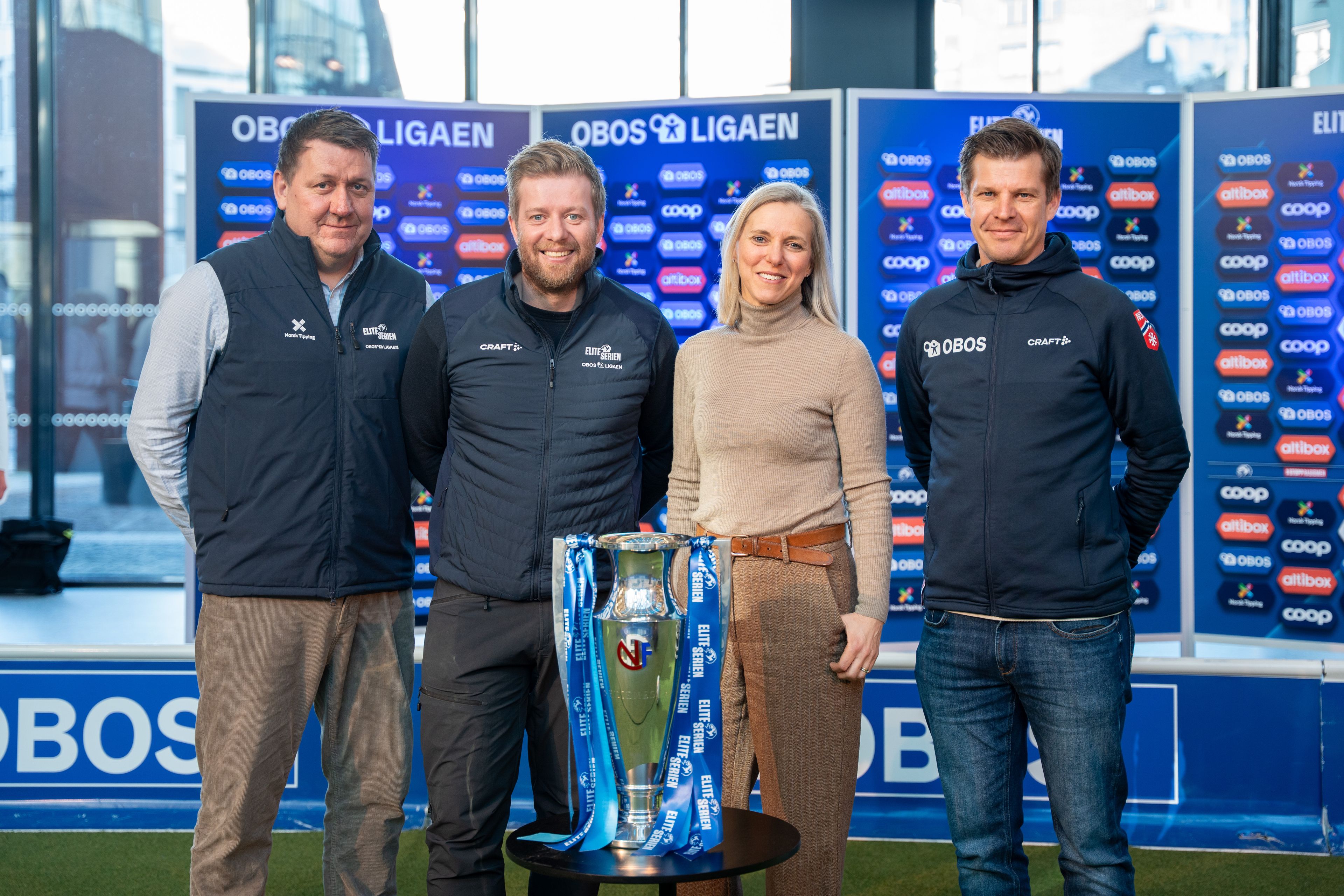 Representanter fra NTF og OBOS stiller opp med Eliteserie-pokalen.