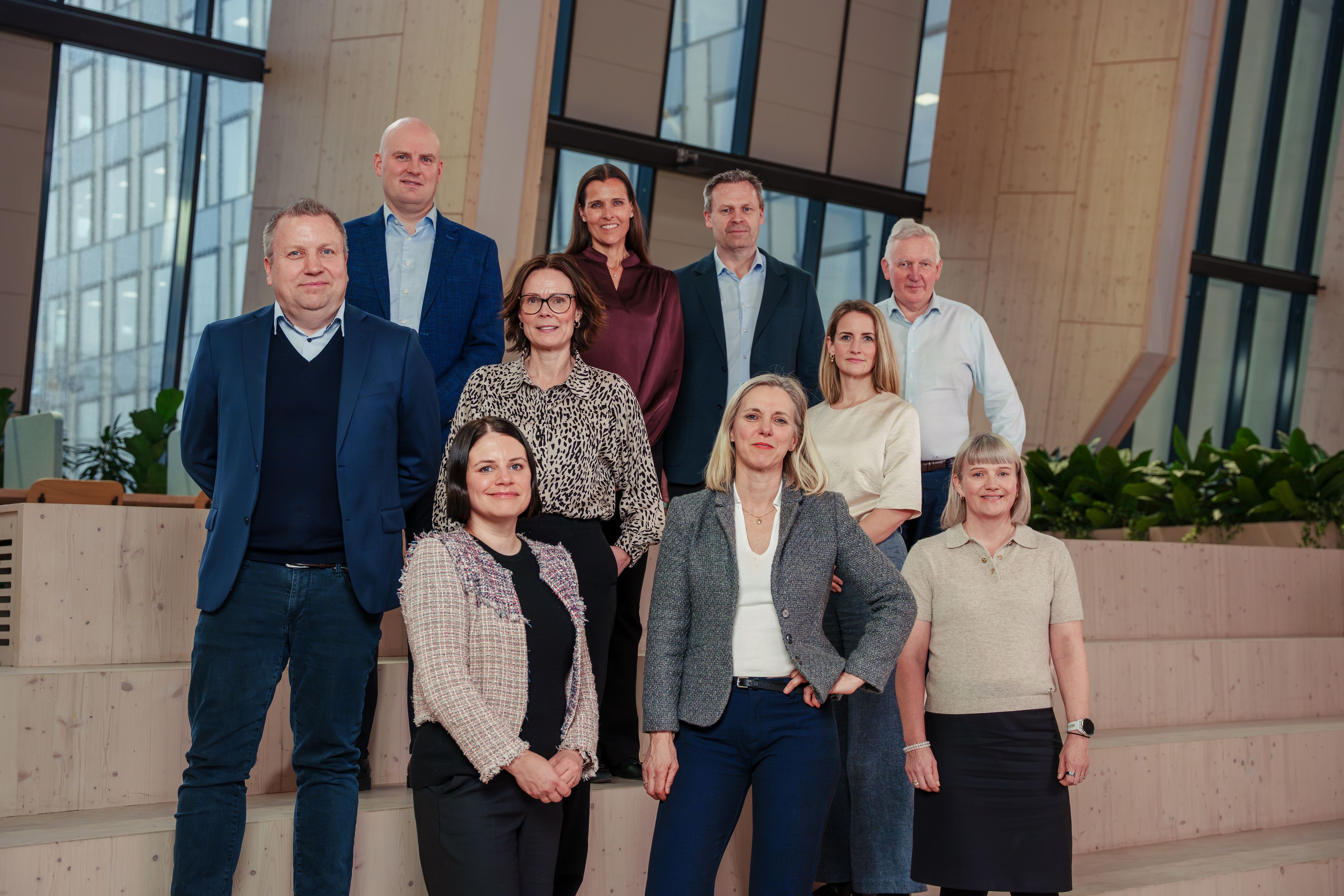 Konsernledelsen i OBOS poserer smilende foran en trapp.