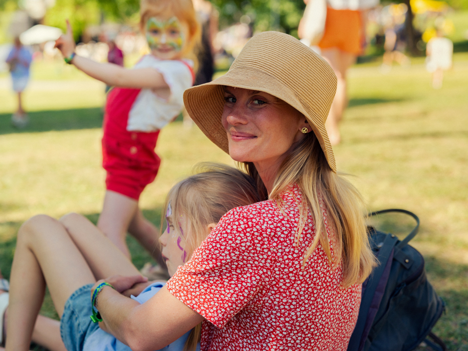 Bild på mamma med barn som sitter i gräset