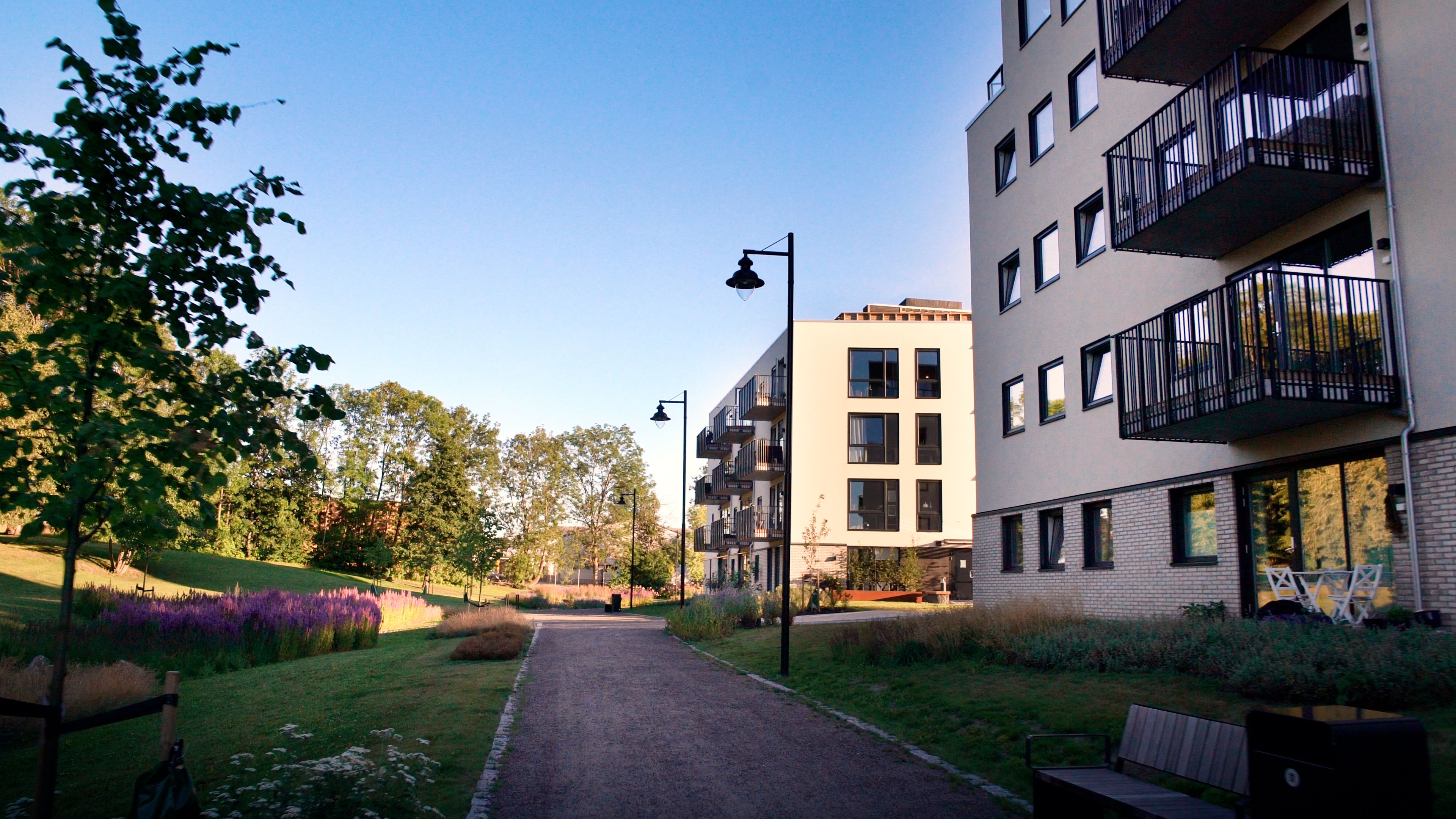 To av blokkene i Teieparken. Foran blokkene er det en gruslagt gangvei med benker og lykter, gressplener, trær og planter.