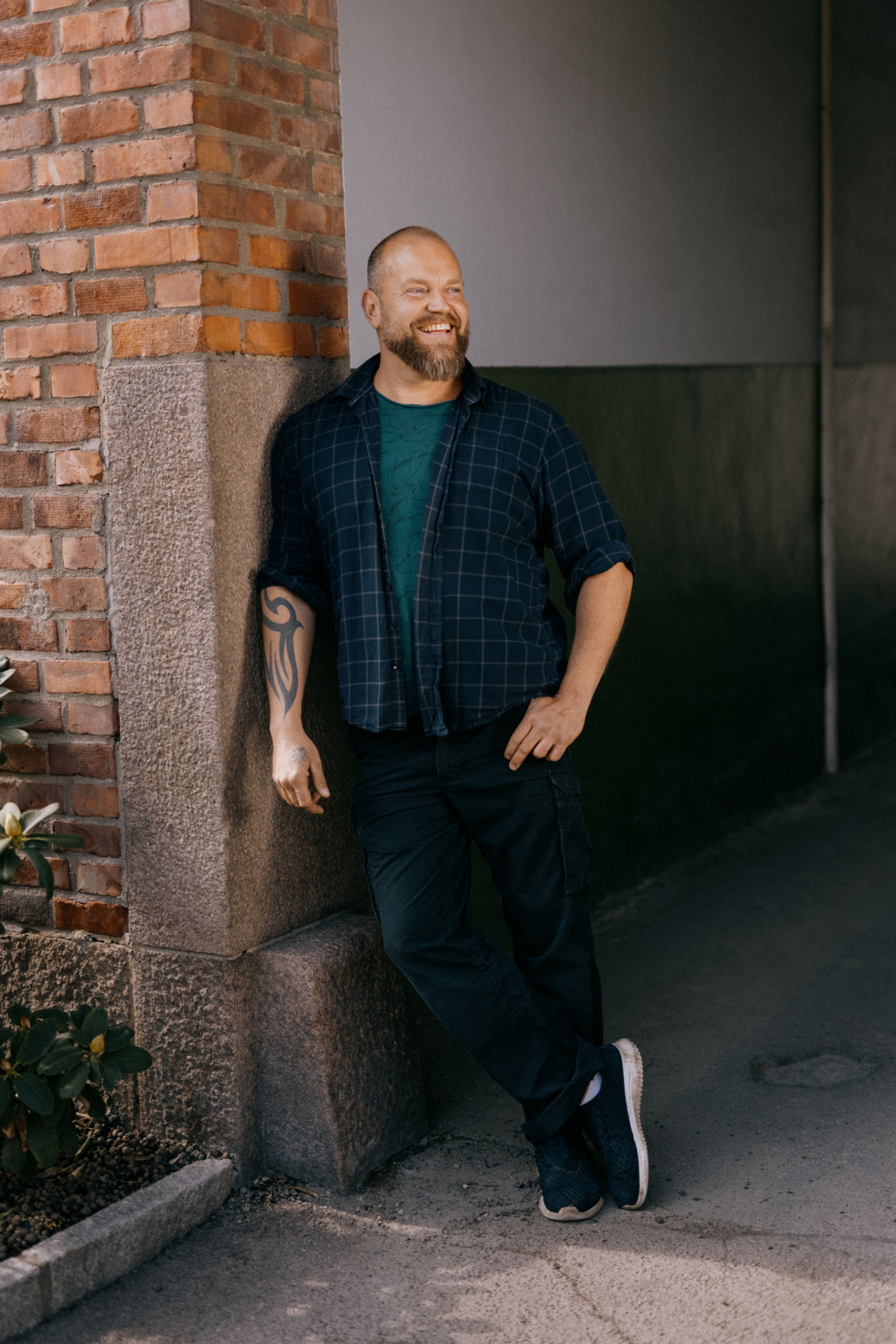 Foto av Thomas Vandraas som lener seg mot en vegg og smiler