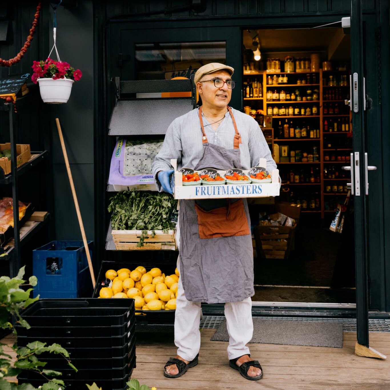 Butikksjefen på Fersken kolonial på Fornebu står utenfor dagligvarebutikken sin med grønnsaker.