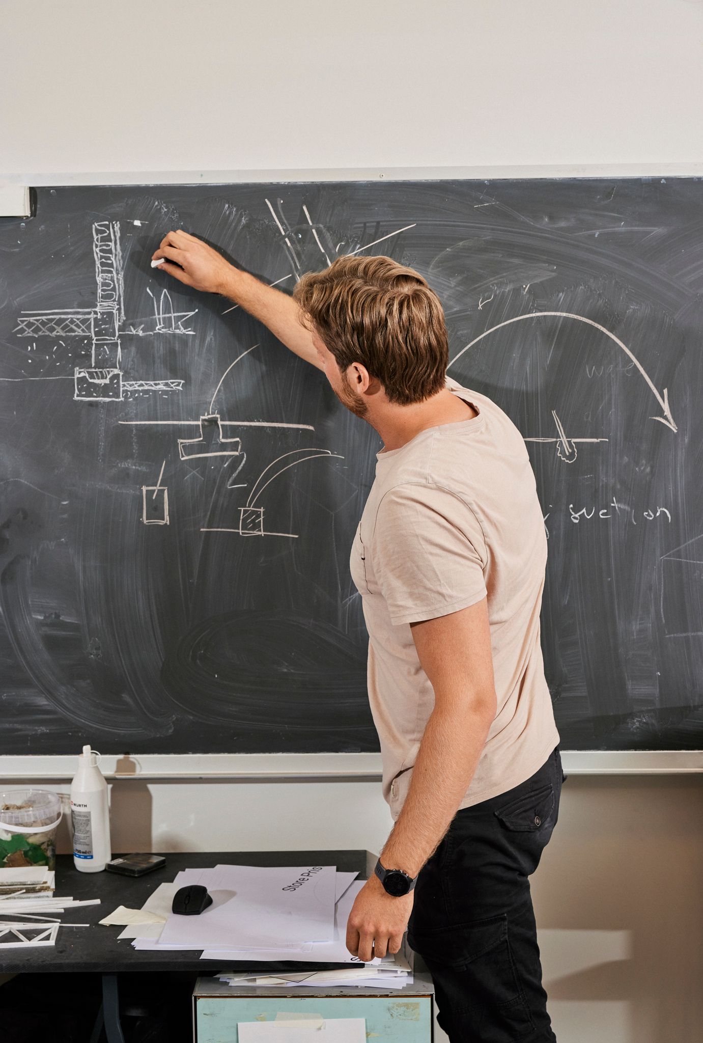 Jonas tegner på en tavle i arbeidsrommet deres på AHO.
