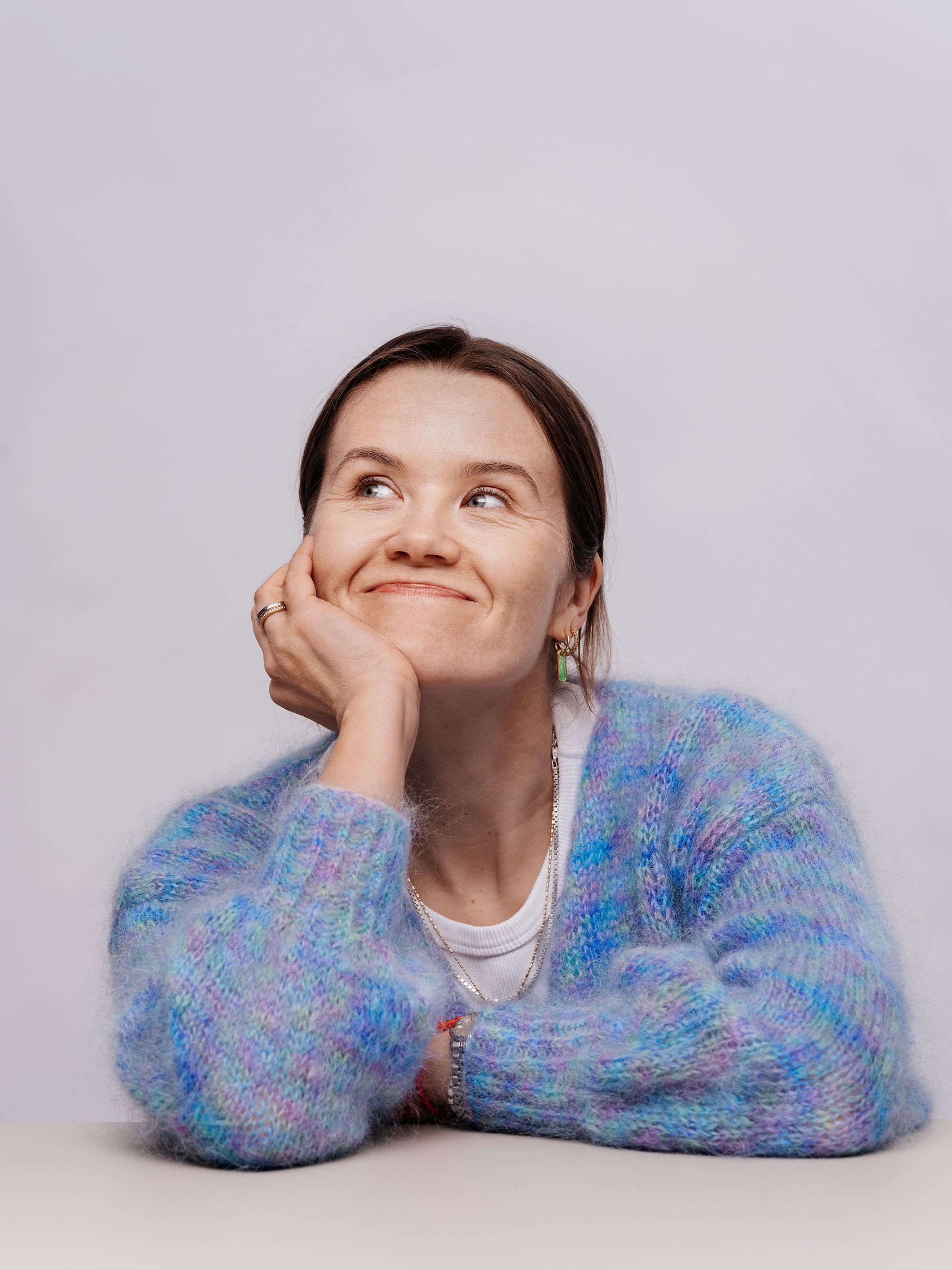 Live Nelvik lener seg over et bord, smiler og ser ut av bildet.